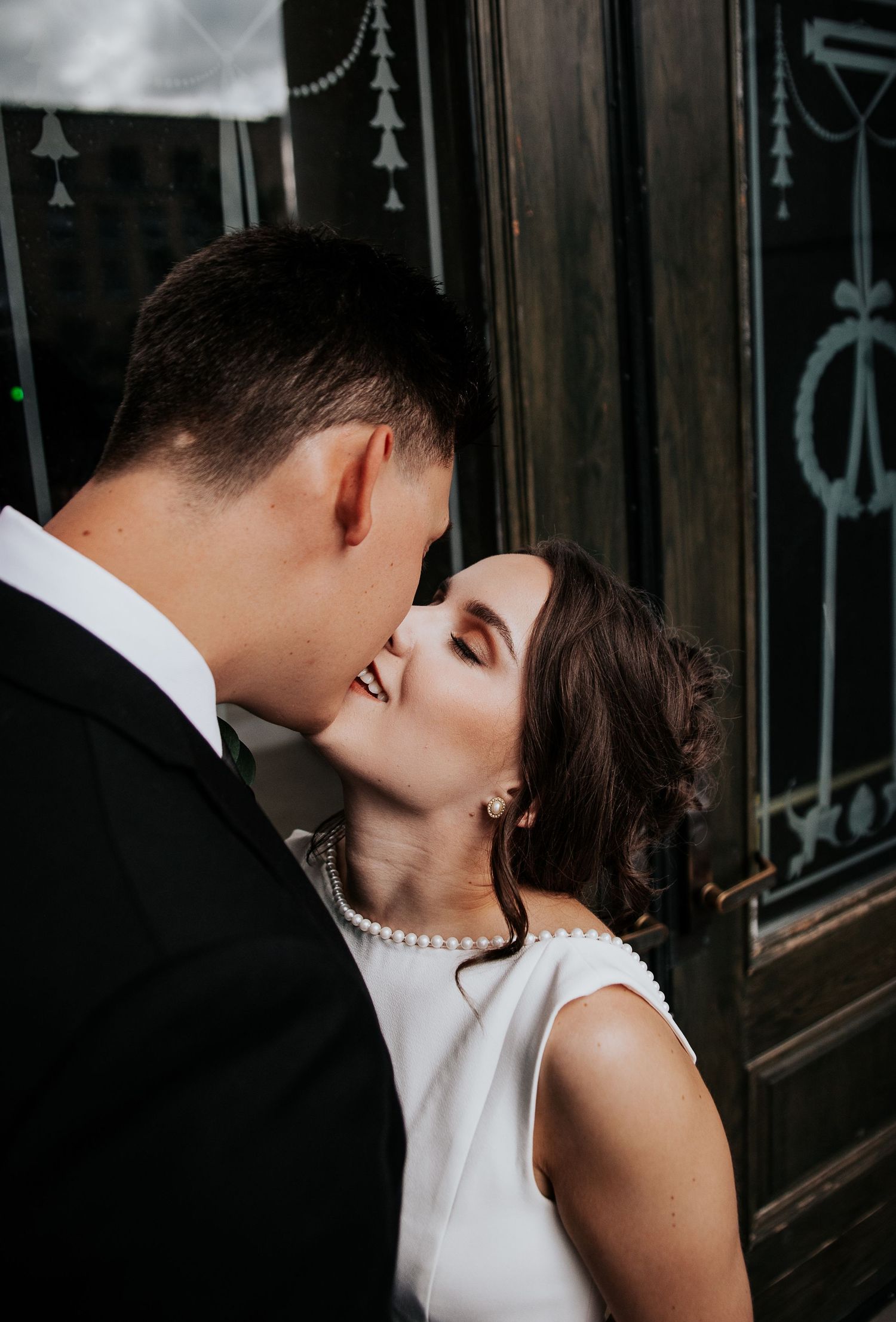 A couple shares an intimate kiss in front of an ornate iron gate in black and white photography during Colorado Springs courthouse wedding