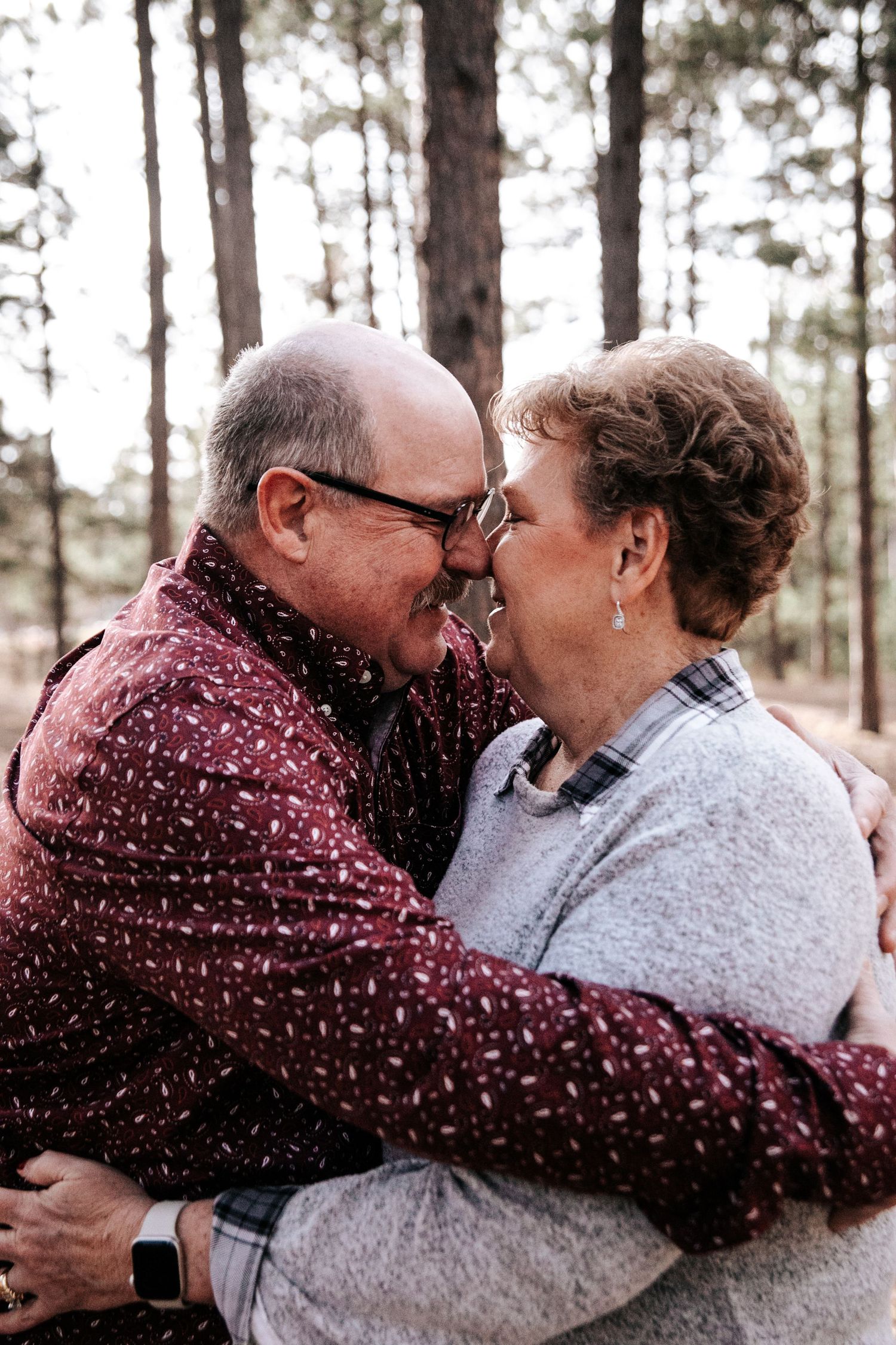 Candid moments of joy and laughter between couple in pine forest.