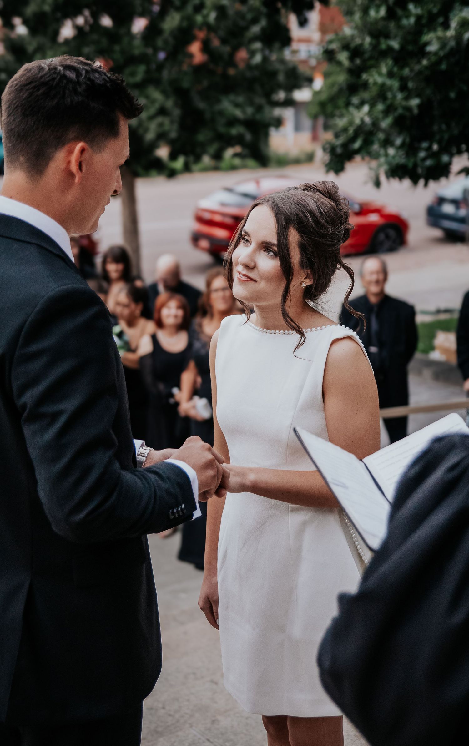Candid wedding ceremony moments captured during vow exchange on city street.