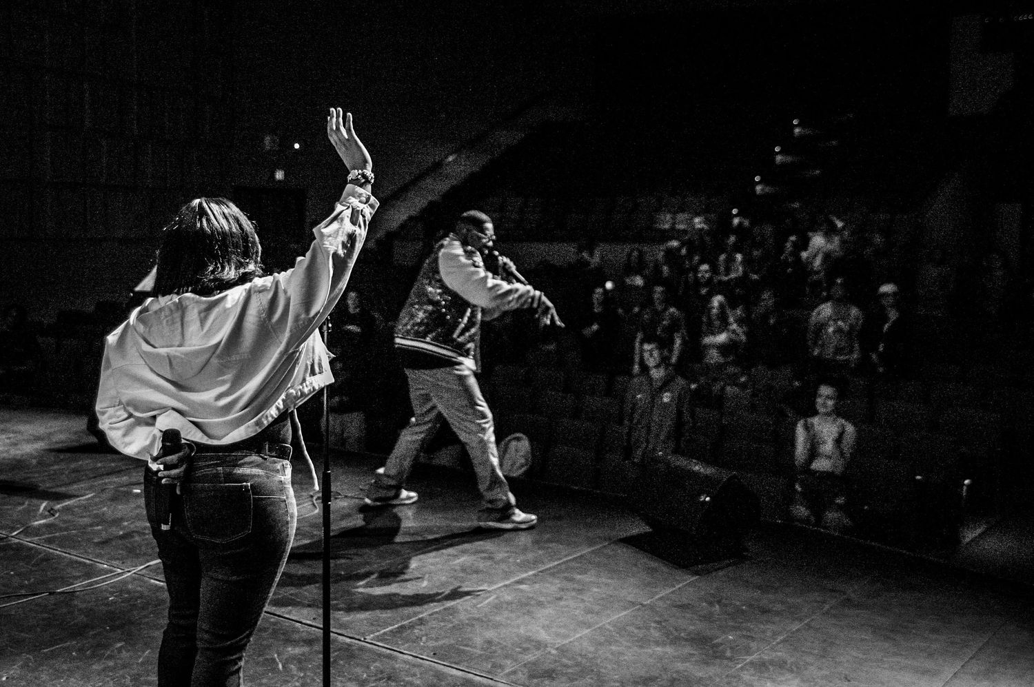 Black and white shot of performers energetically entertaining a crowd on stage.