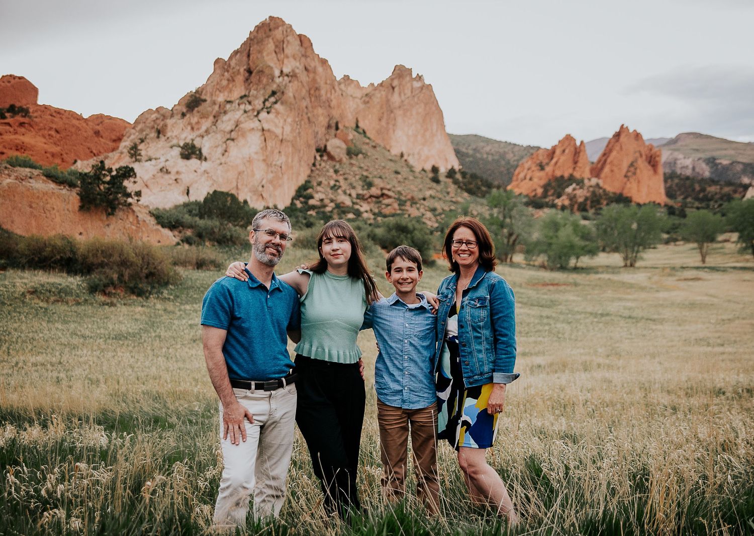 Family portrait captured at Garden of the Gods park in Colorado with dramatic red rock formations in background.