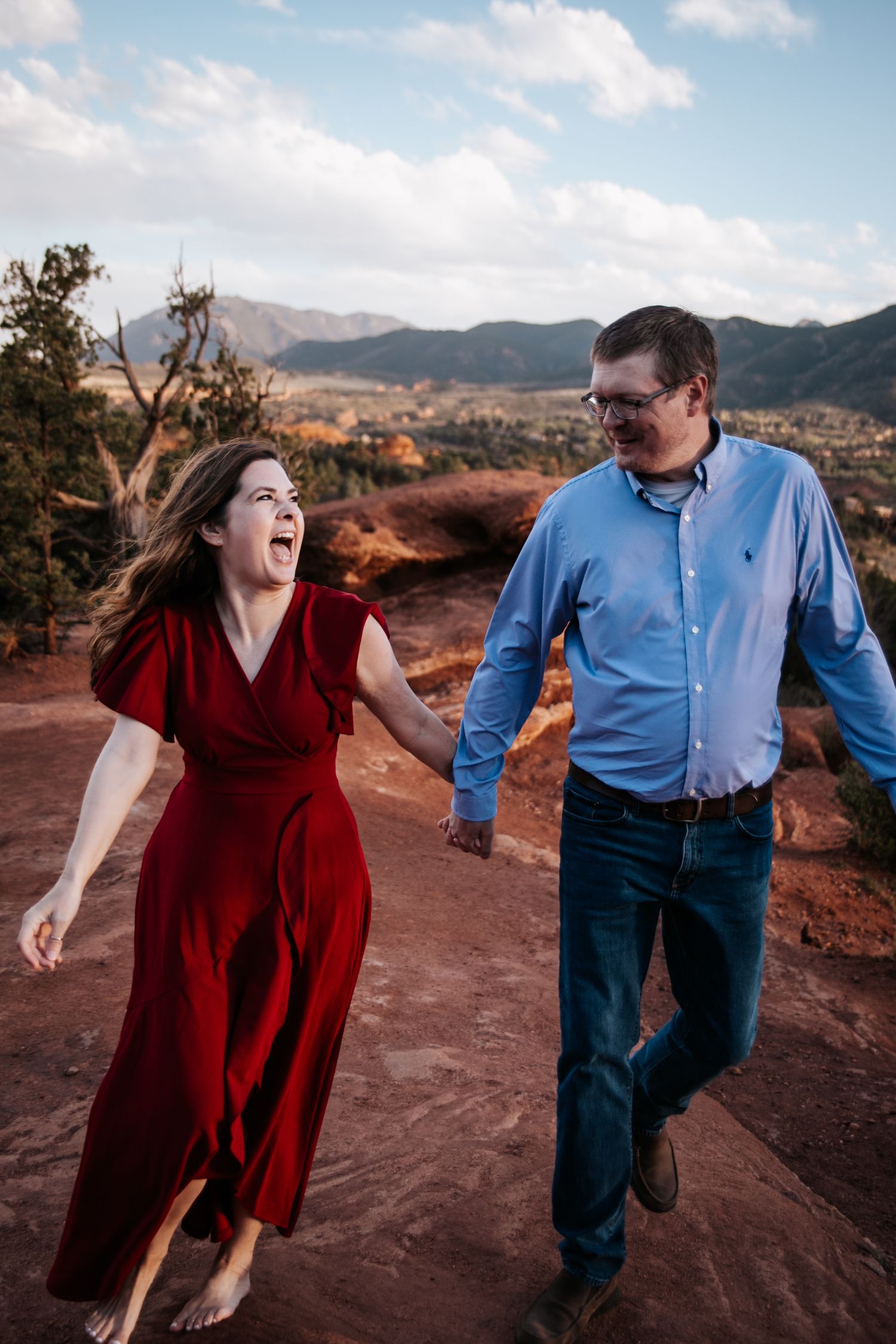 A couple shares a candid moment while walking along a scenic red rock trail.