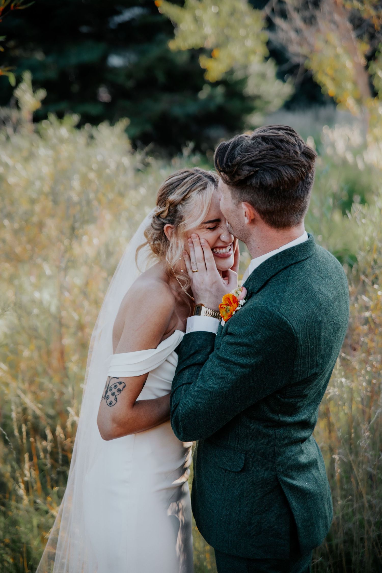 Tender moment between couple in outdoor wedding setting with tall grass.