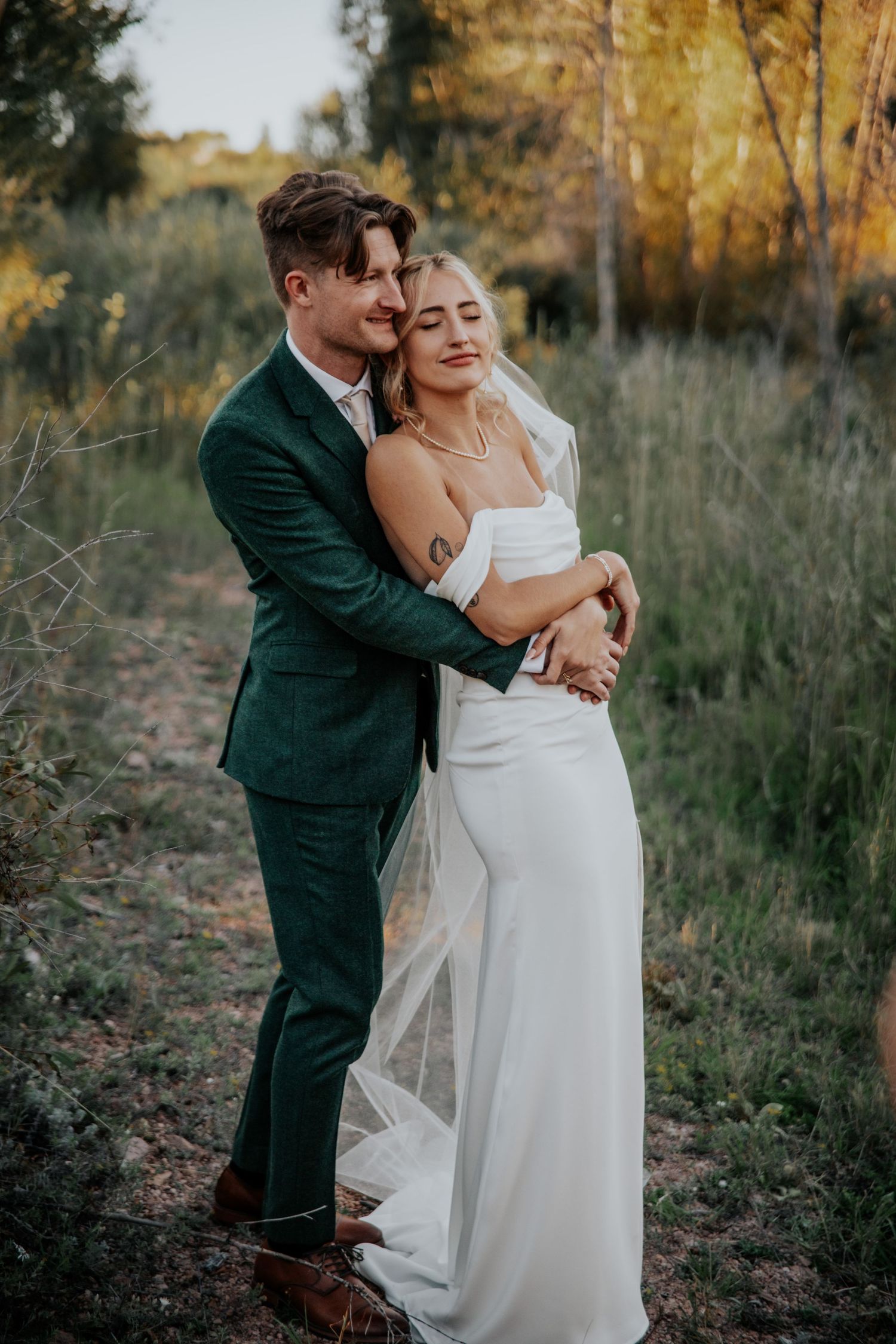 Intimate wedding portraits in natural setting with bride in white gown and dark suit.