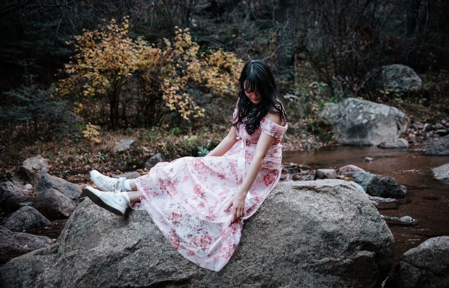 A delicate pink dress draped over natural stone in a serene creek setting.