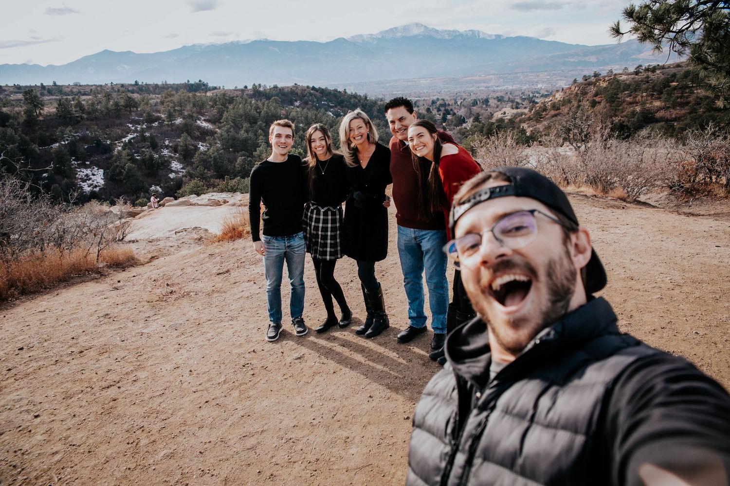 Family gathering for casual group photos with mountain scenery in the background.