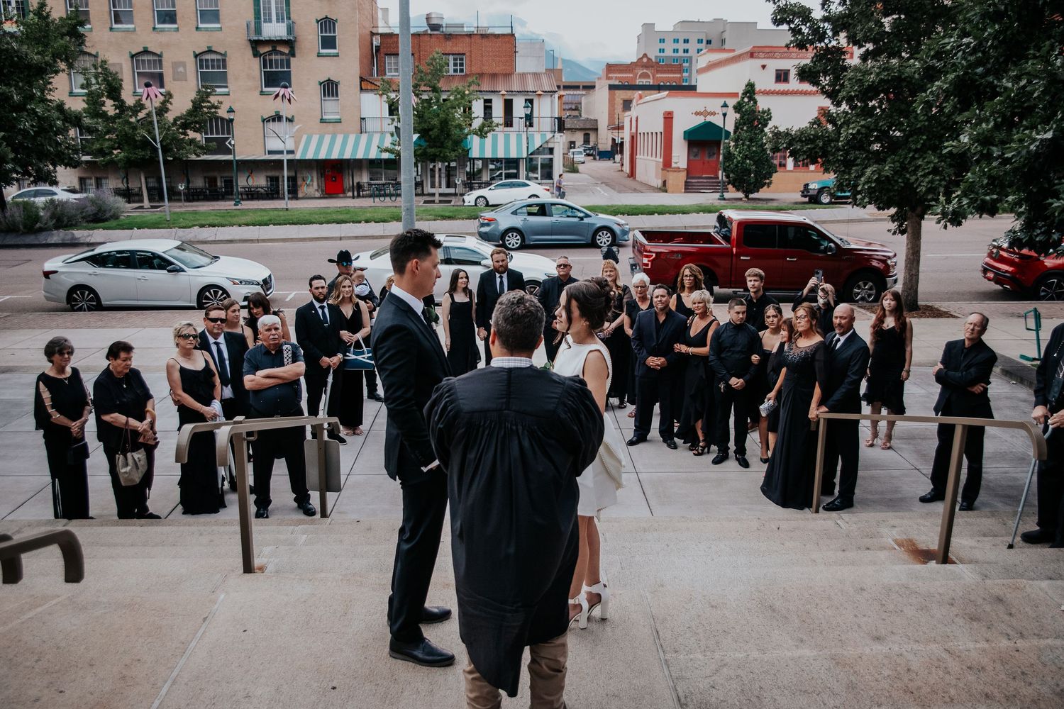 A group of formally dressed people gathered outside a building for a special event.
