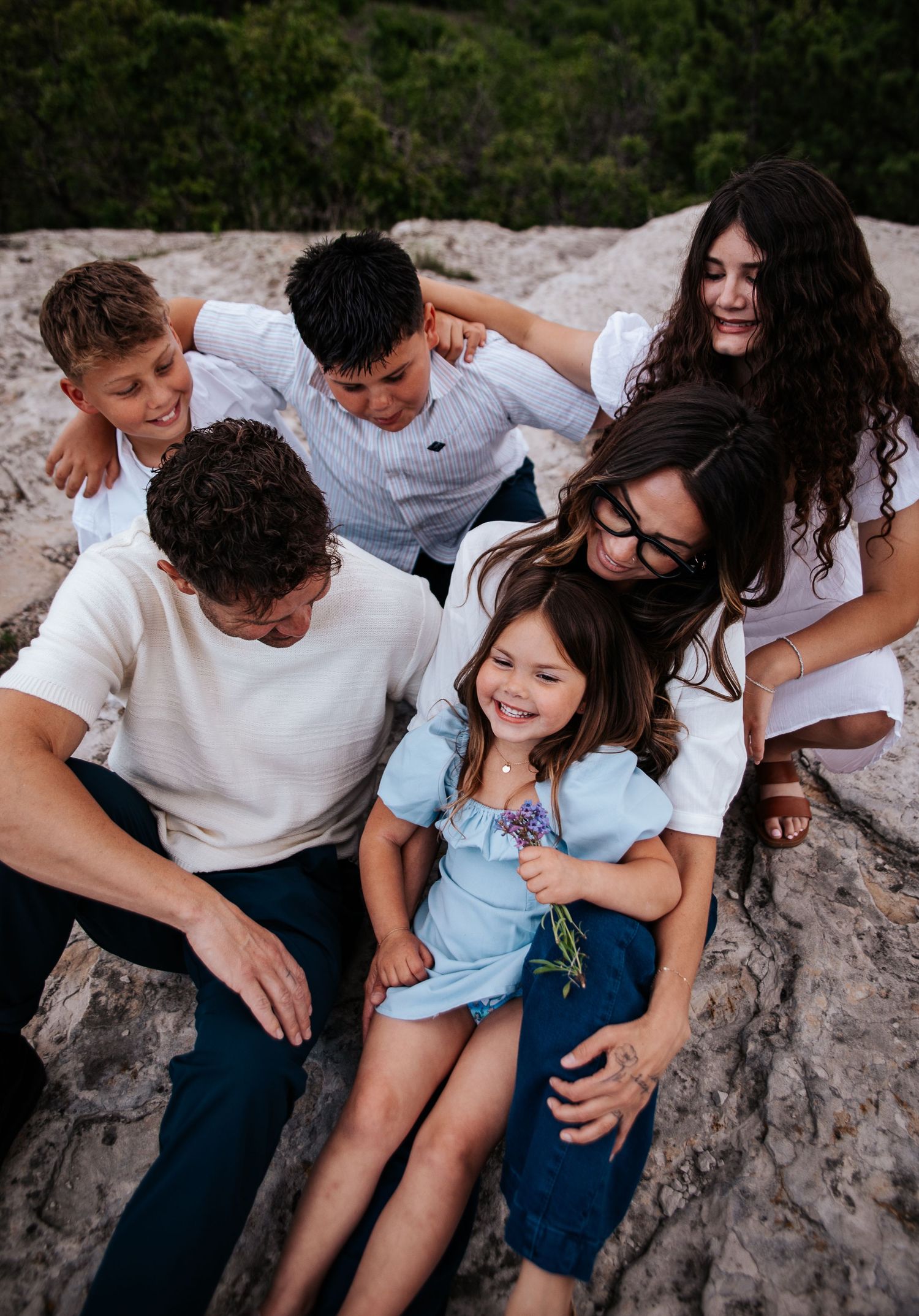 Candid laughing moments captured of a family sitting together on rocky terrain at Ute Valley Park in Colorado Springs