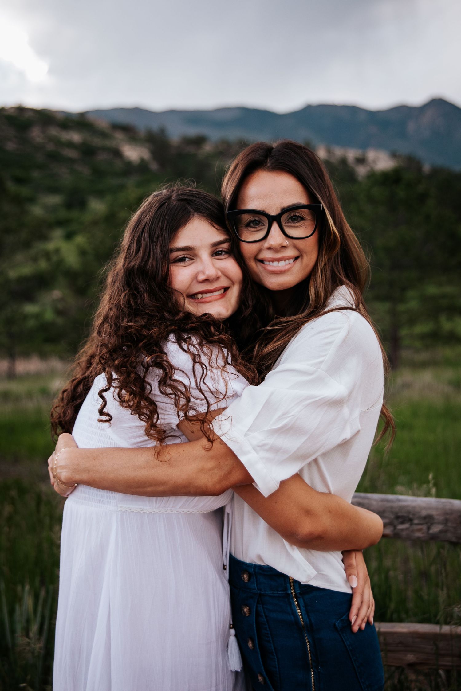 Mother and daughter embrace and smile warmly against mountain landscape backdrop at Ute Valley Park in Colorado Springs