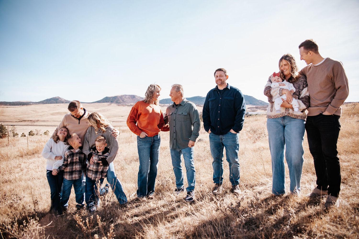 Group of people walking together on a scenic hillside trail against a desert landscape backdrop.