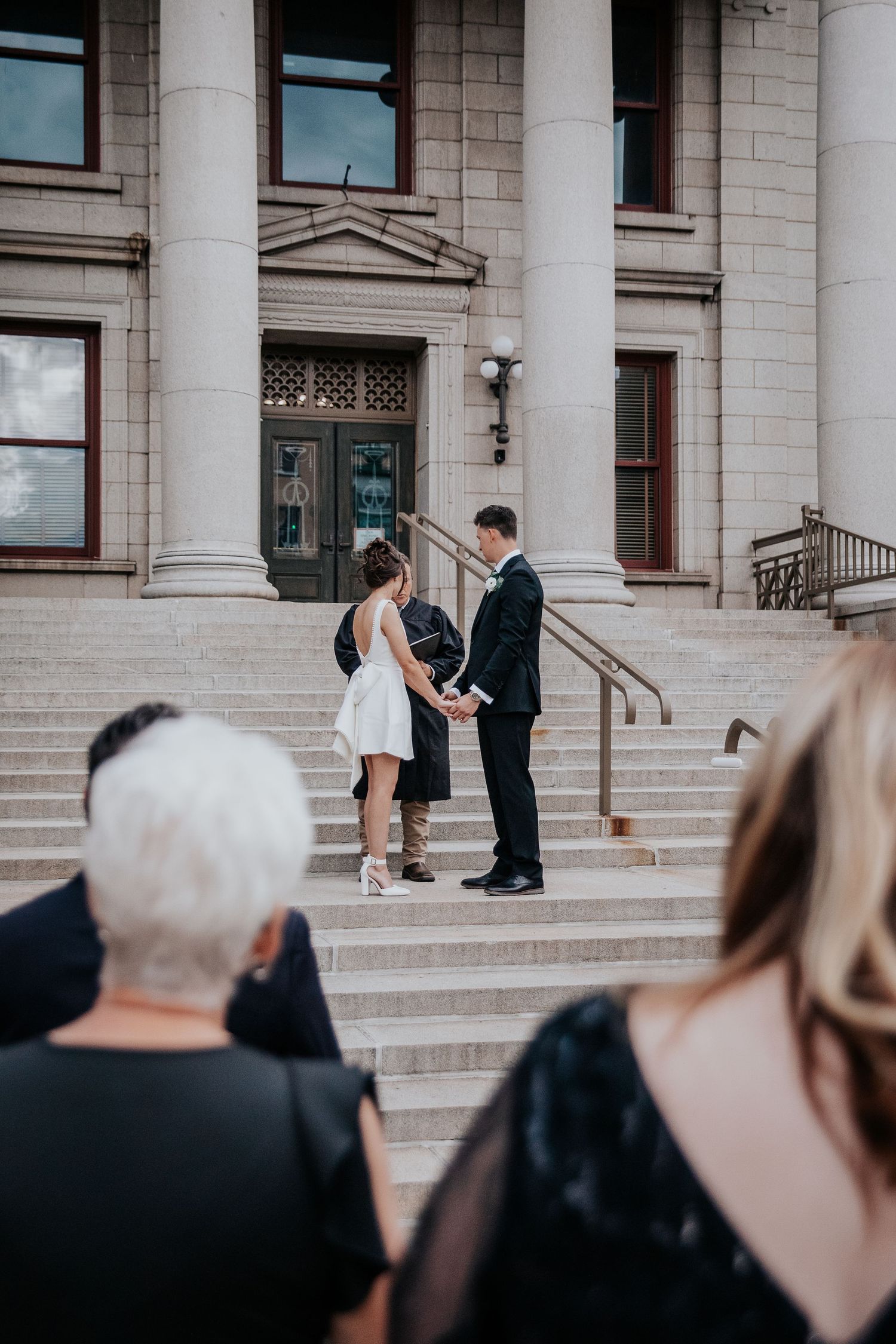 A wedding ceremony taking place on grand stone steps of a historic building with white columns.