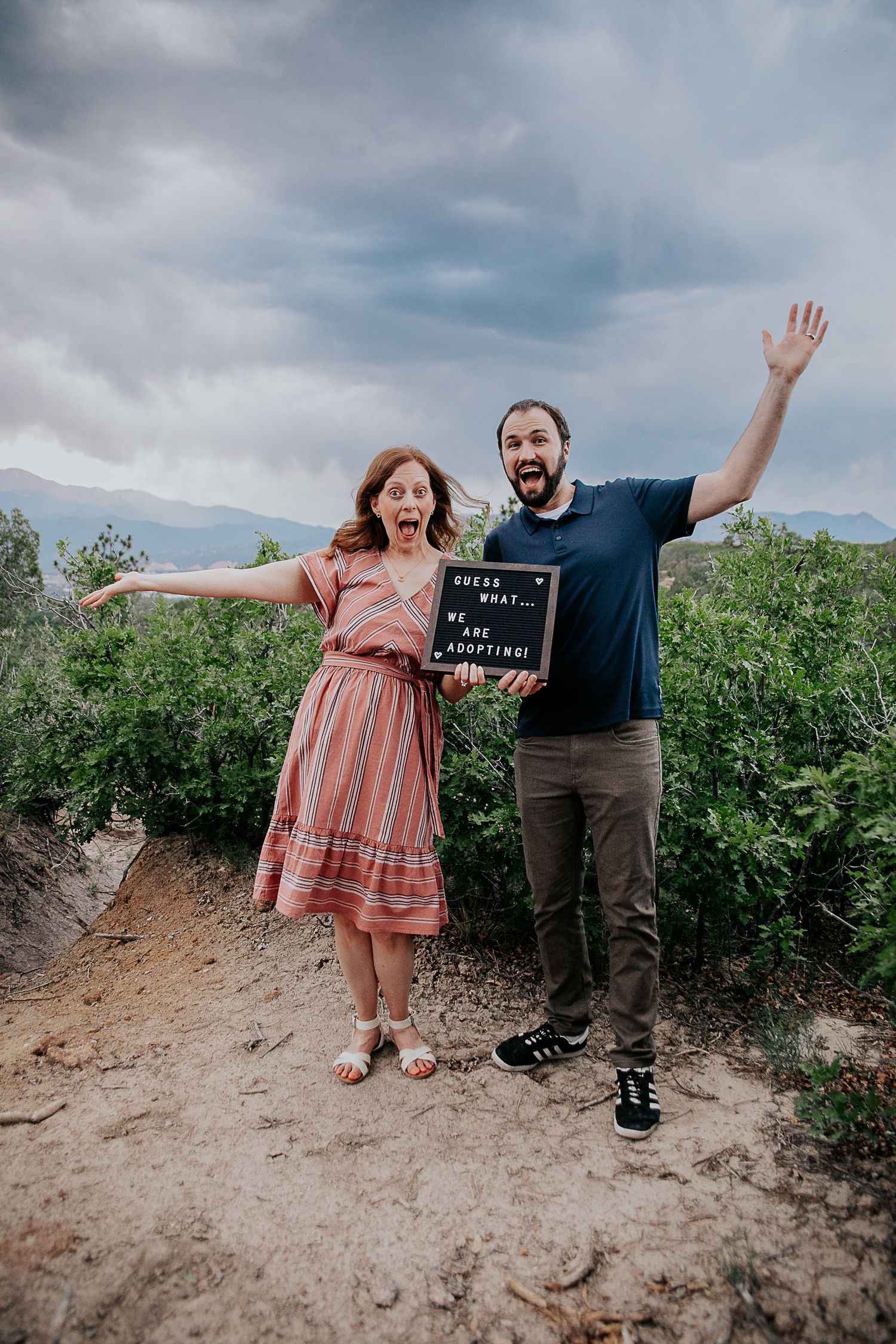 A couple celebrates with joyful poses and energetic jumps in a sunny vineyard setting.