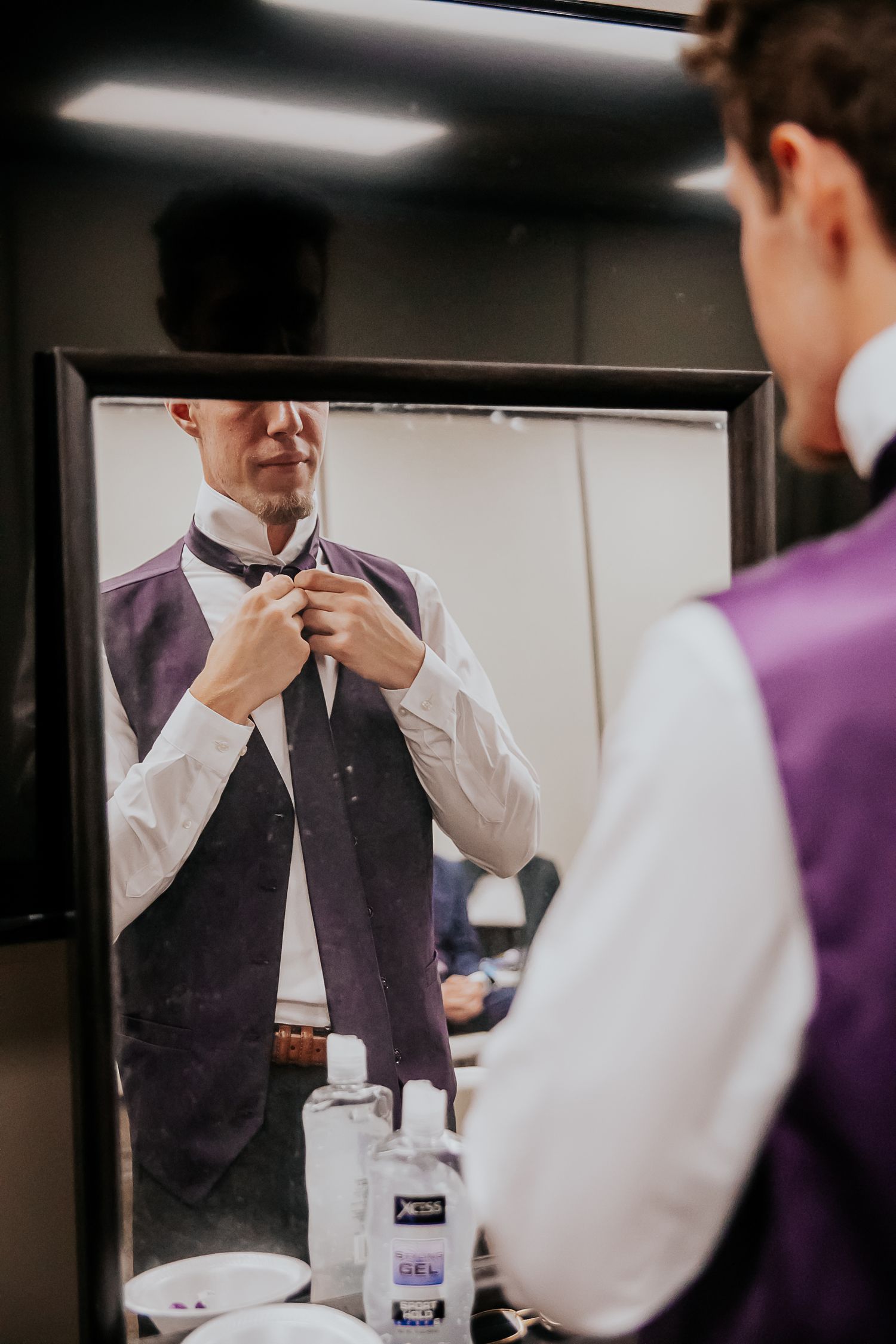 Groom adjusting his tie in the mirror during Kansas city summer wedding, from Colorado Springs wedding photographer Jasmine Morse