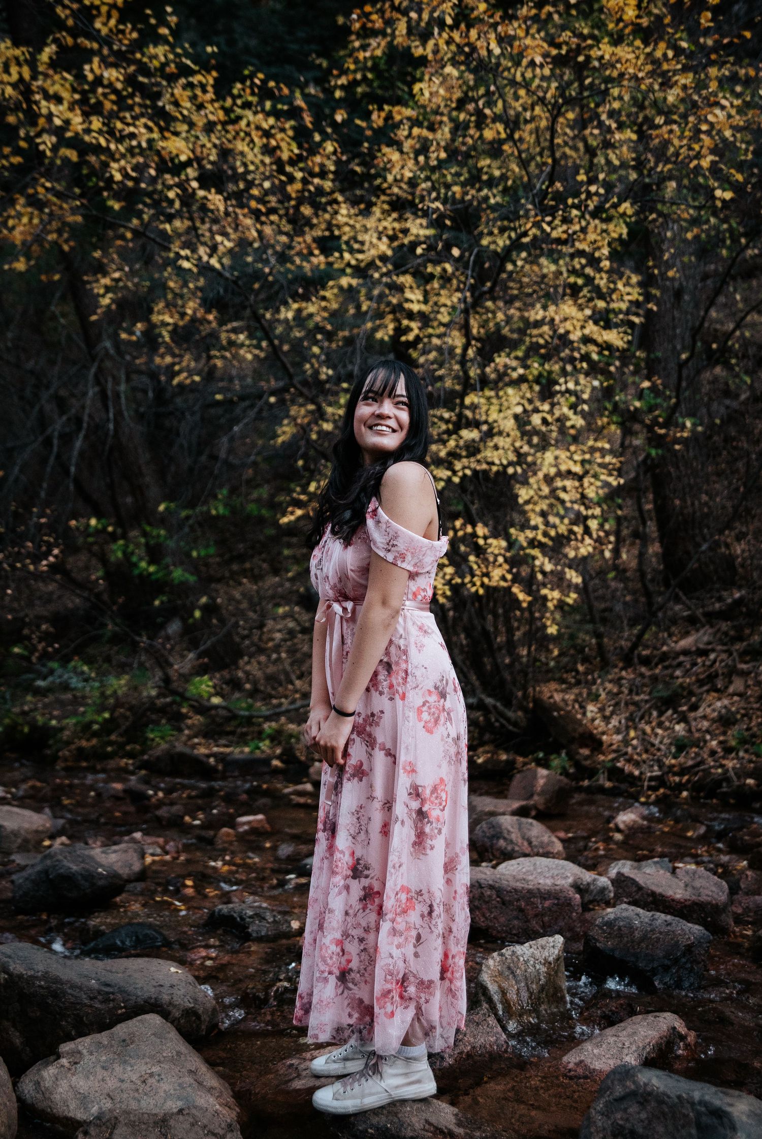 A soft portrait against golden autumn trees wearing a pink floral dress.