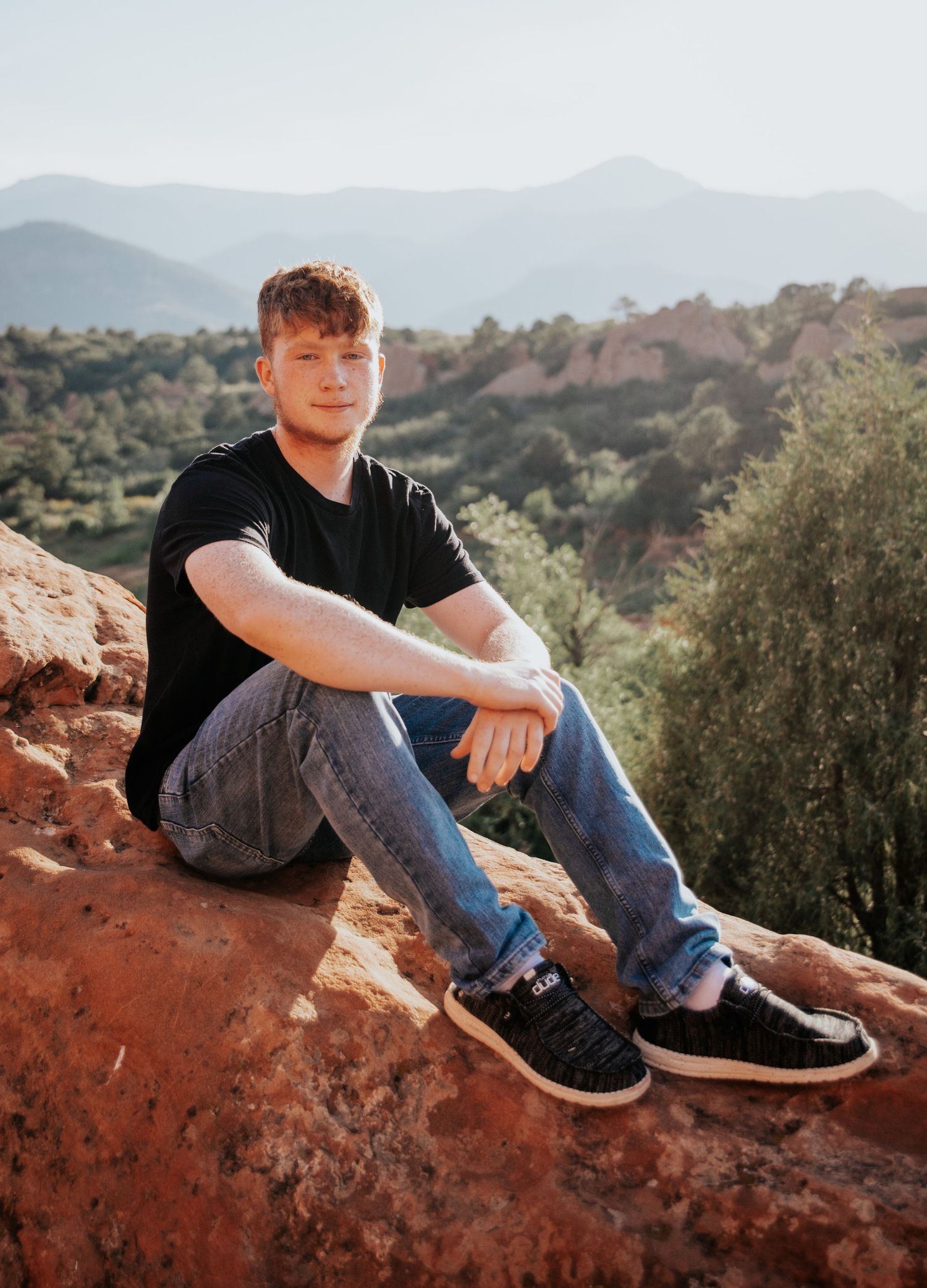 Young man on red rocks at Red Rock Open Space during senior photo session in Colorado Springs