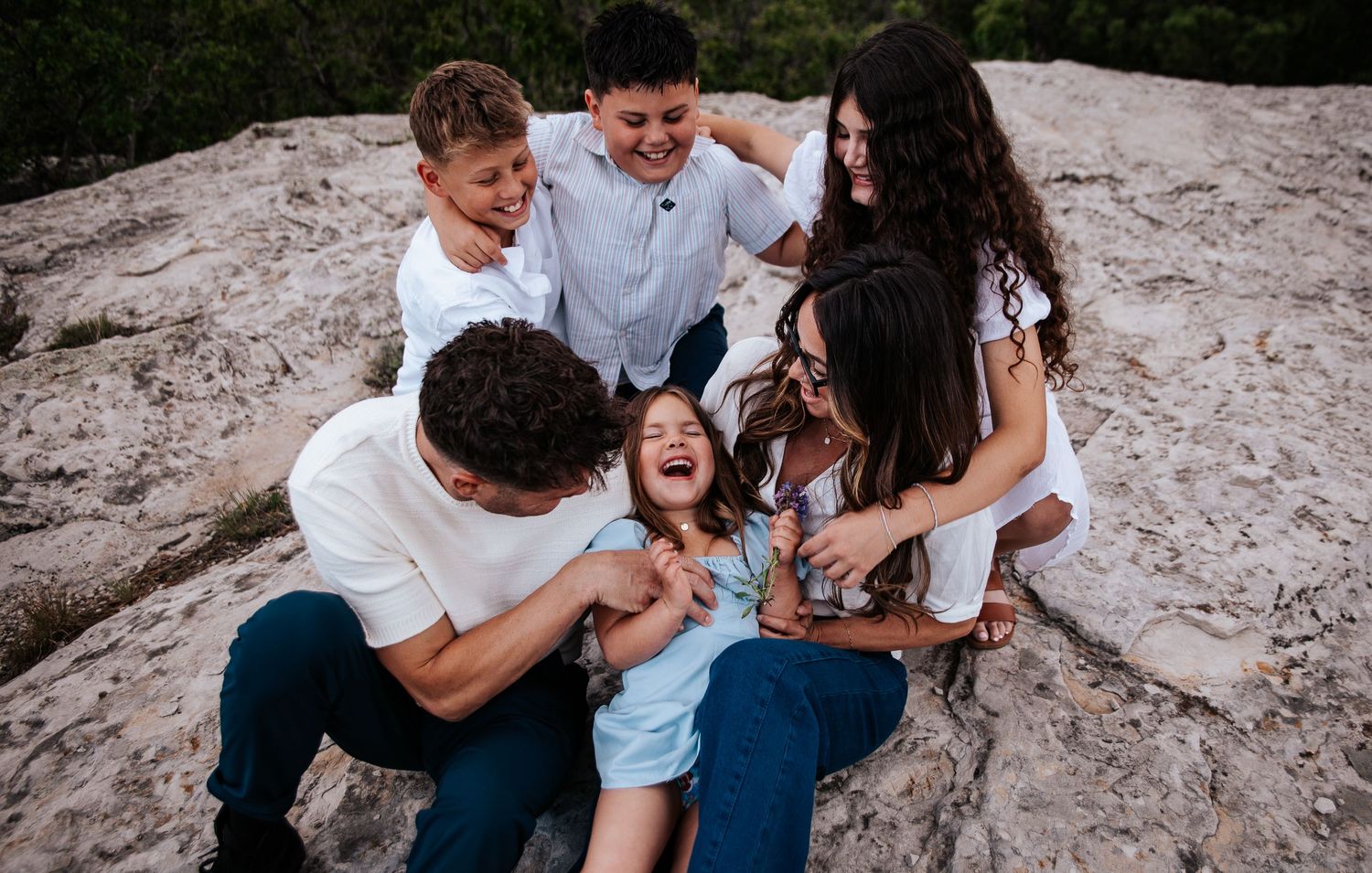 Family shares joyful candid moments while sitting together on natural rock formations at Ute Valley Park in Colorado Springs