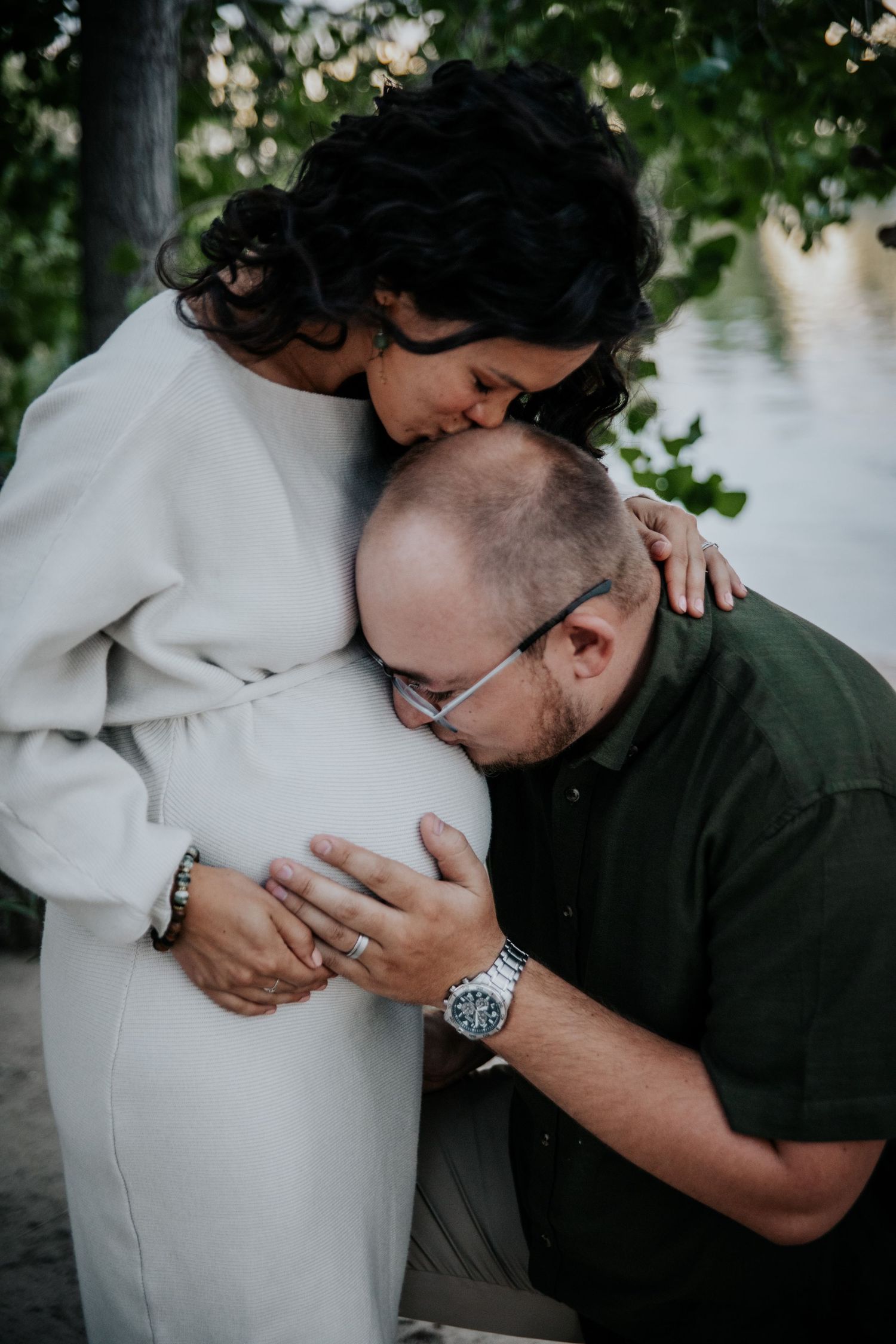 Intimate outdoor maternity photoshoot showing couple embracing with pregnant belly between them.