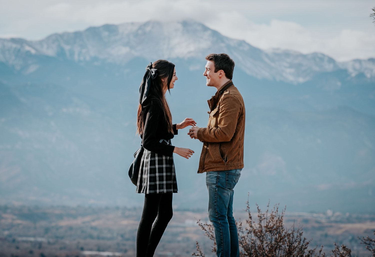 A couple shares intimate moments against a mountain backdrop in a series of candid engagement photos.