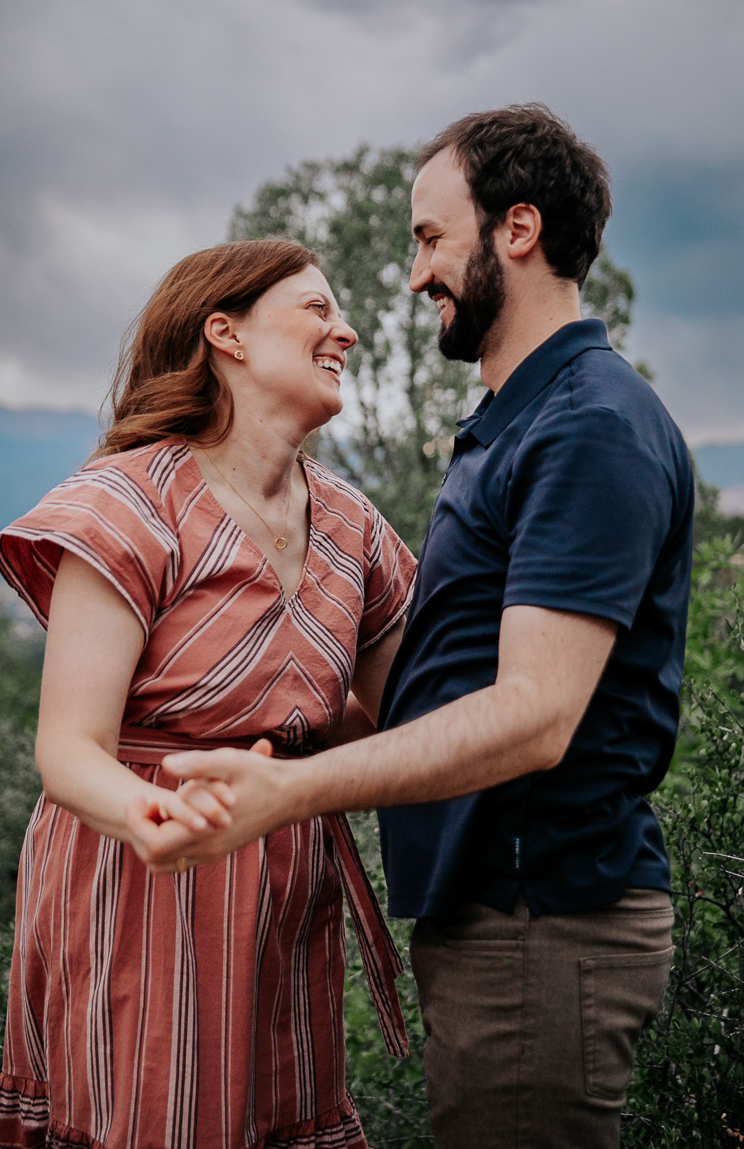 A romantic outdoor photoshoot featuring a couple in casual attire against a cloudy sky.