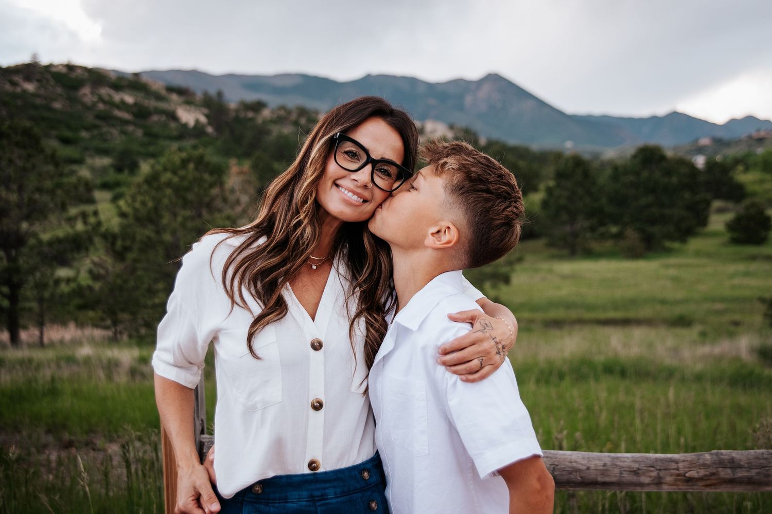 Mother in glasses and child share affectionate moment with mountain backdrop at Ute Valley Park in Colorado Springs