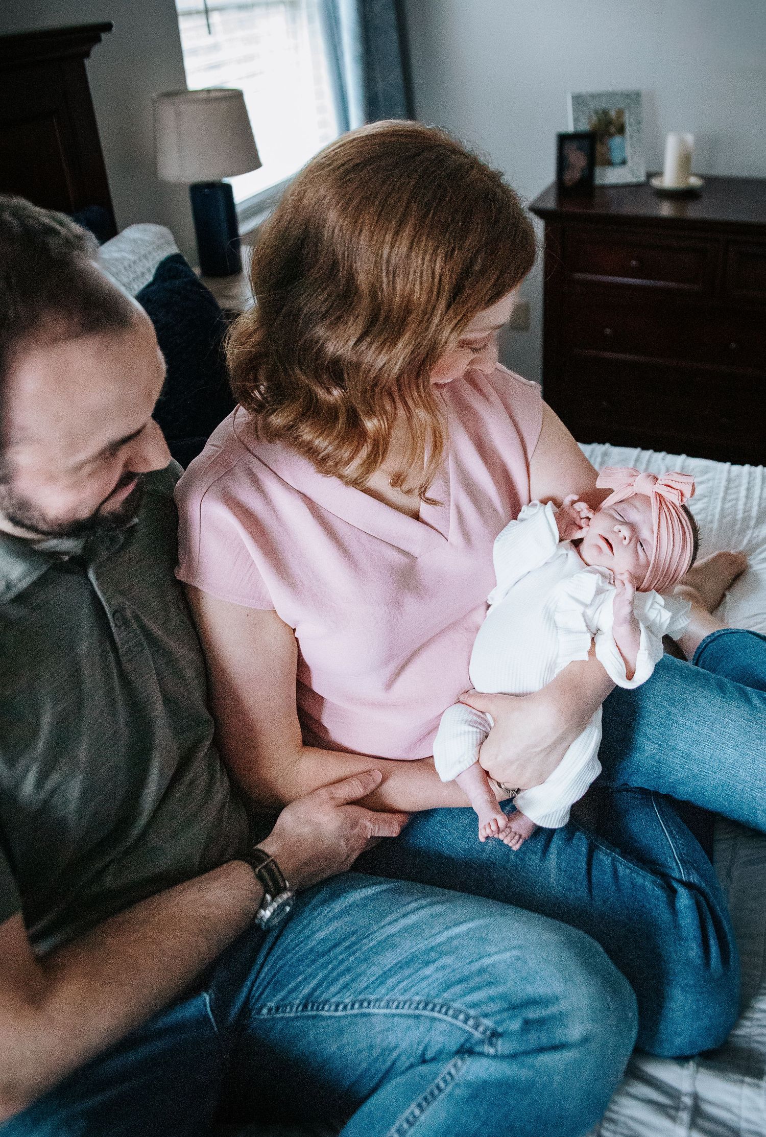 A series of candid photos showing a family cuddling together on a blue couch with their newborn.