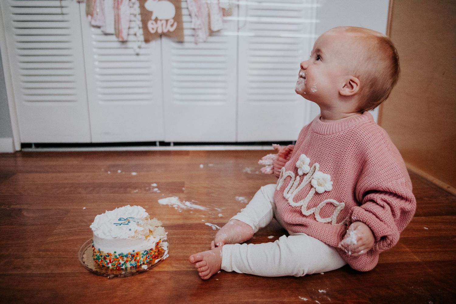 A first birthday celebration setup with pink decorations and a small smash cake.