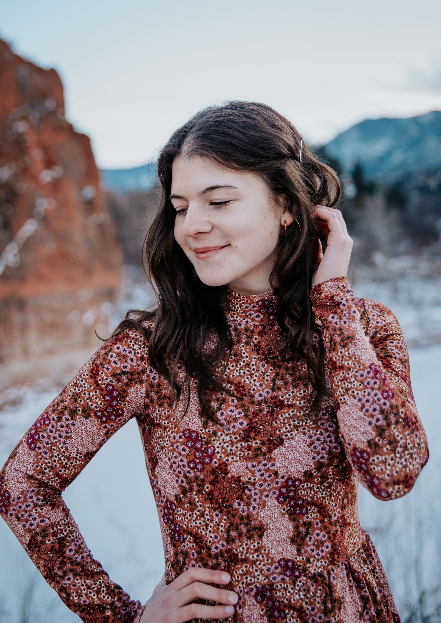 Candid moments captured in a burgundy floral dress against a winter landscape.