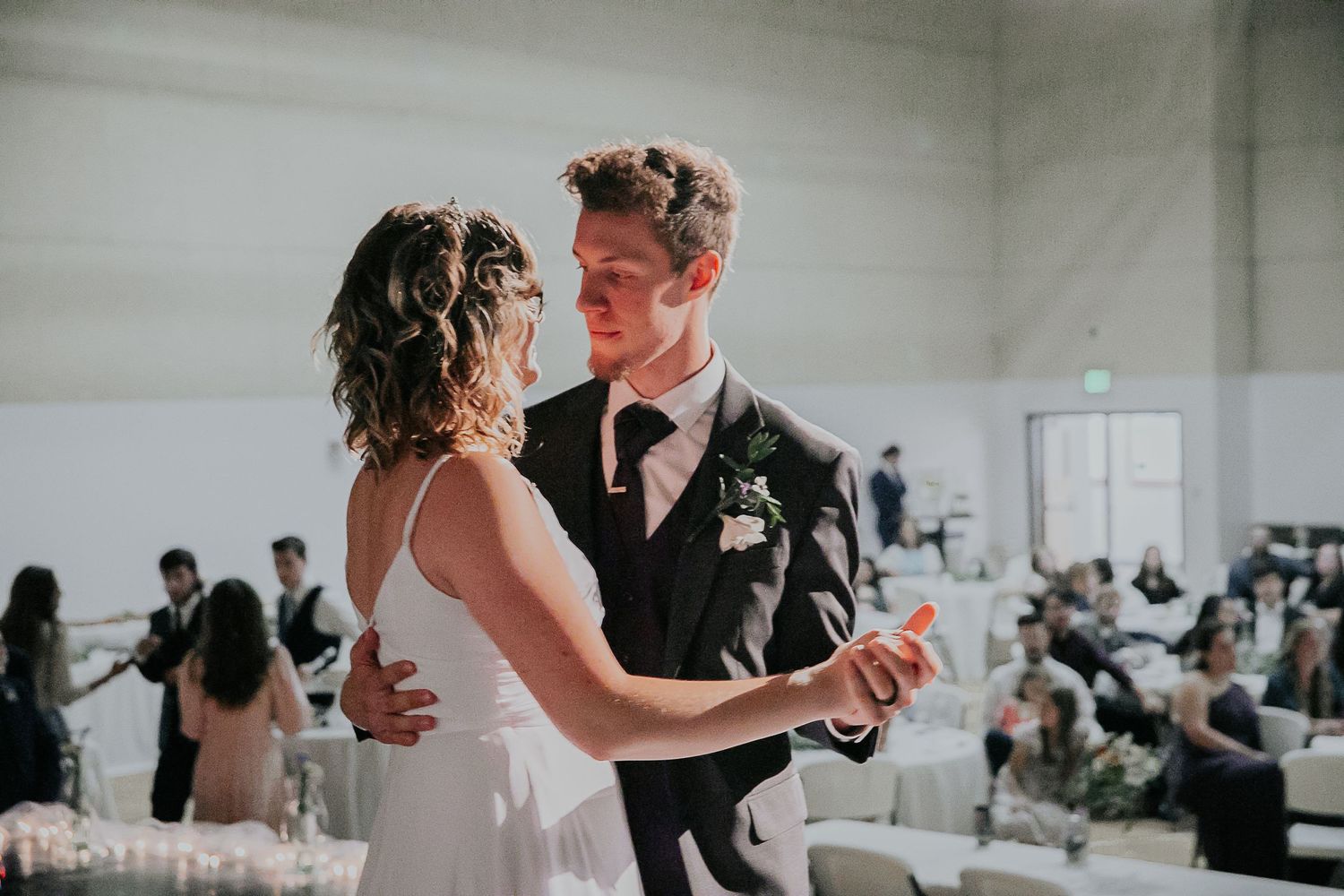 Couple dances together at their wedding reception in bright industrial space.