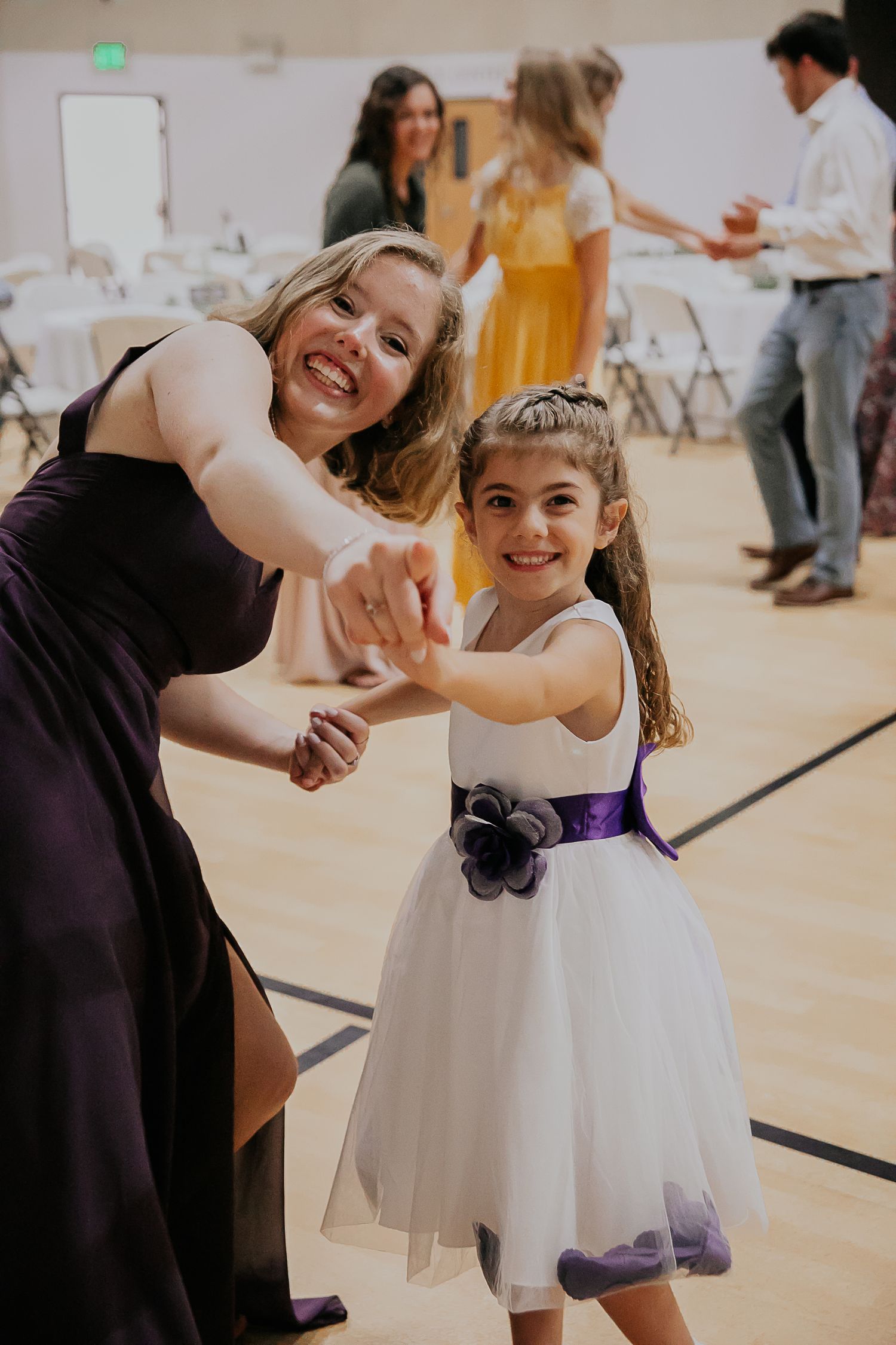 Young dancers twirling and enjoying themselves at an indoor community event.