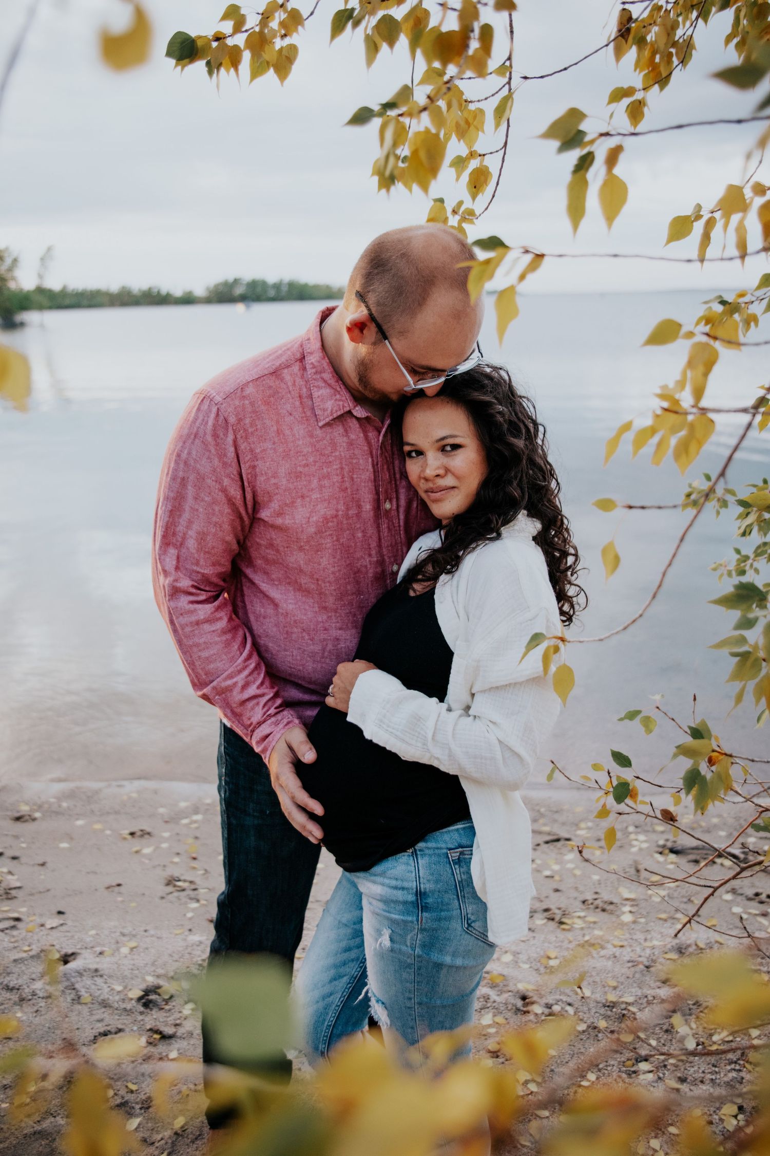 Romantic beach photoshoot with fall foliage and water in the background.