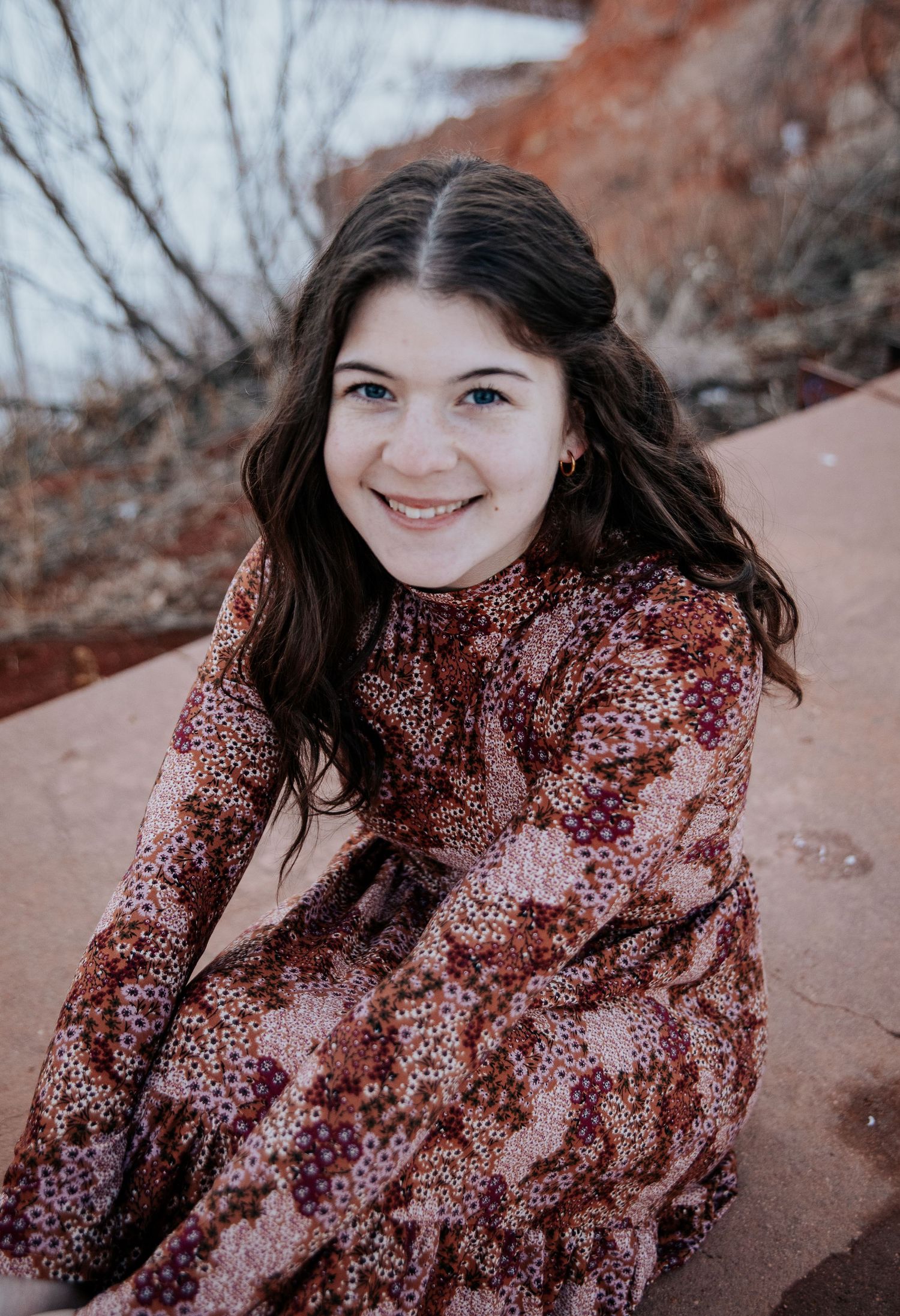 Portrait session on red rocks showing candid expressions and floral dress details.