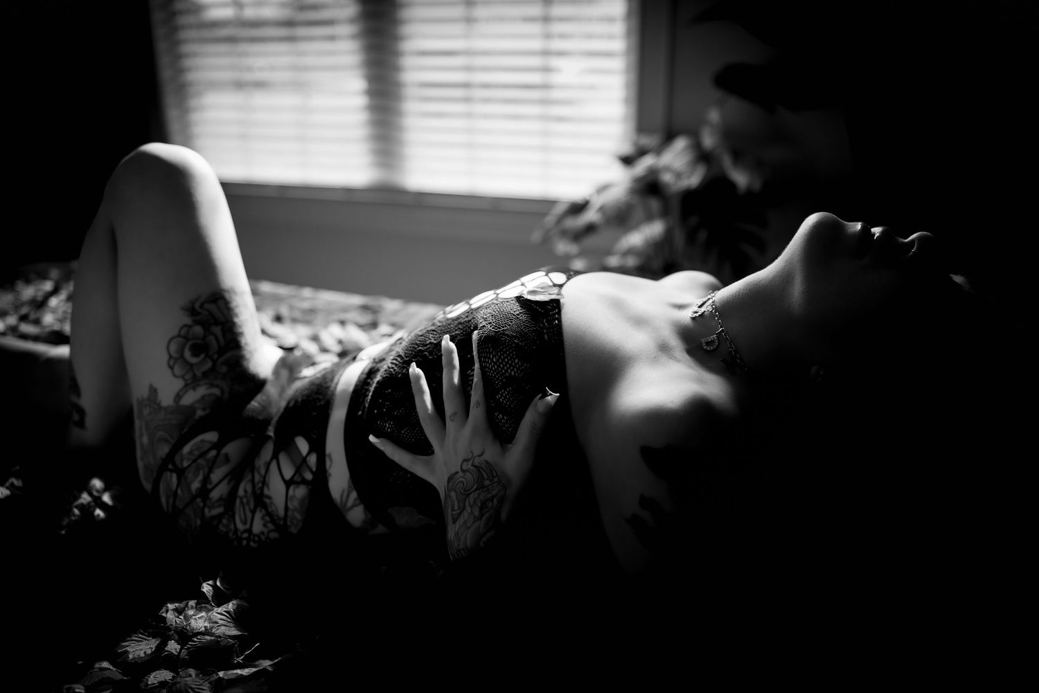 Artistic black and white boudoir photo with venetian blind shadows.
