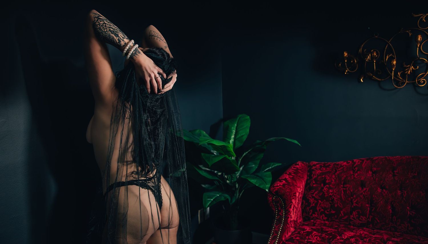 A moody bridal boudoir photo of a woman with black veil and black lingerie in moody lighting creates an intimate atmosphere.