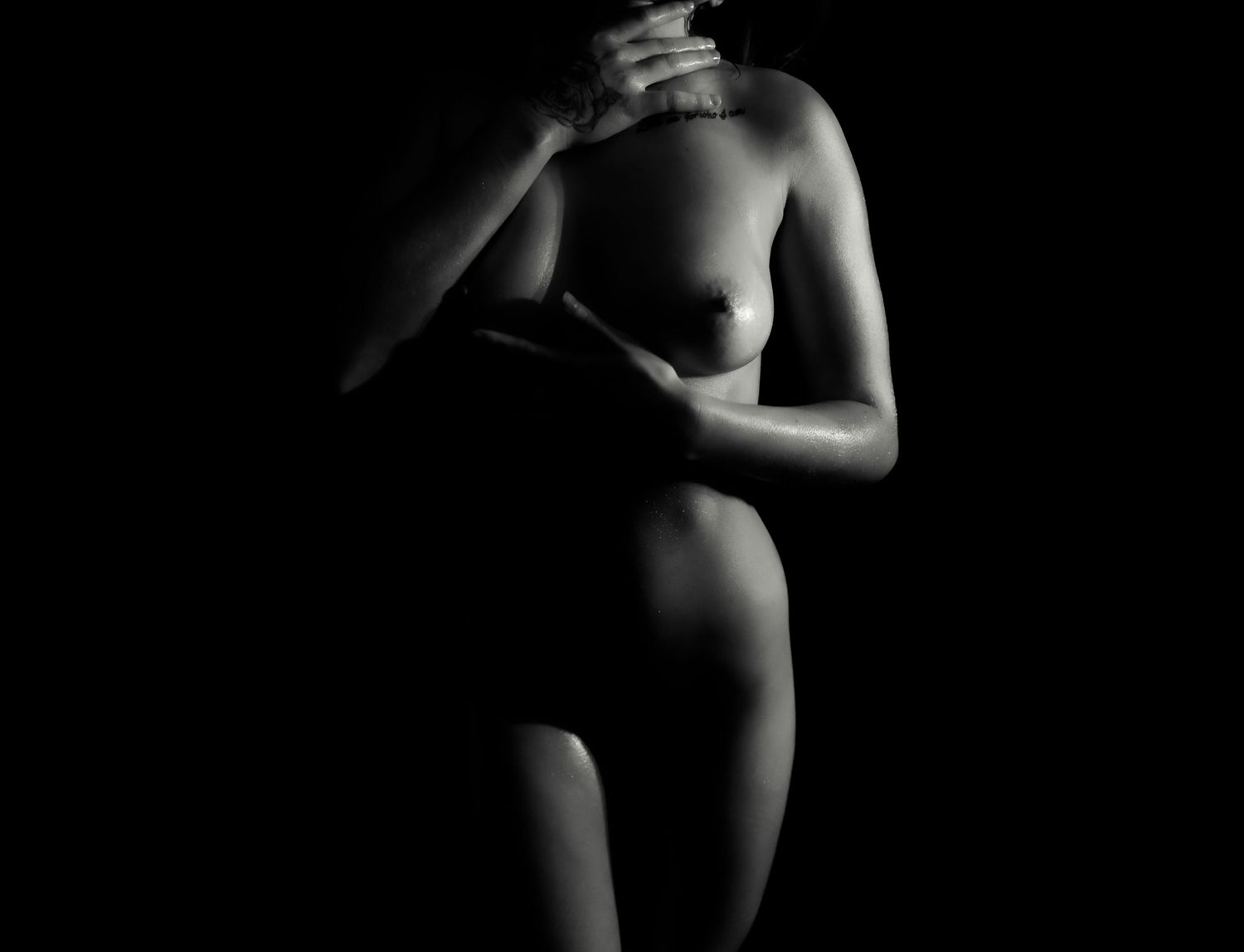 Artistic black and white nude boudoir body scape woman silhouette showing graceful poses against a dark background.