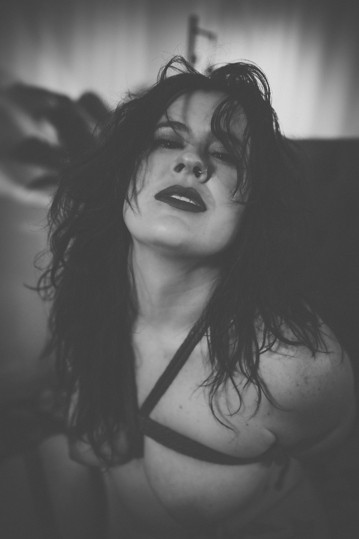 A dramatic black and white boudoir portrait showing a woman tied in rope with dark tousled hair and bold lipstick in an artistic style.