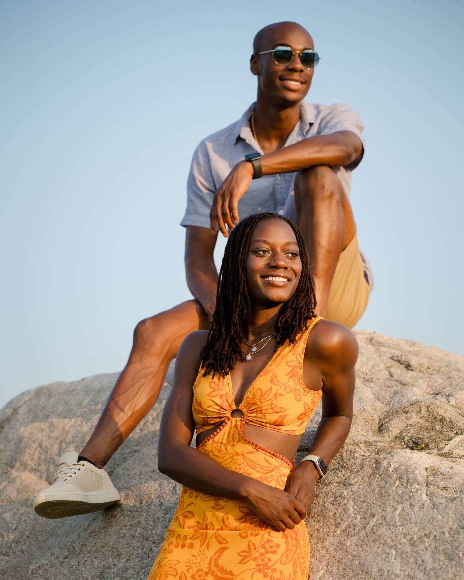 Twins pose together on rocky terrain during sunset, summer photo session.