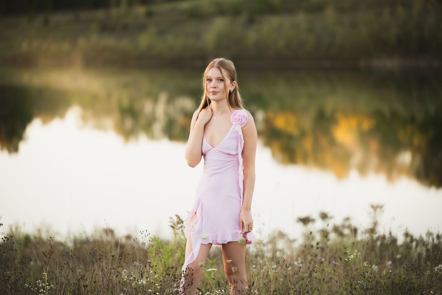 Portrait session in a field at golden hour with soft lighting and natural scenery for senior girl.