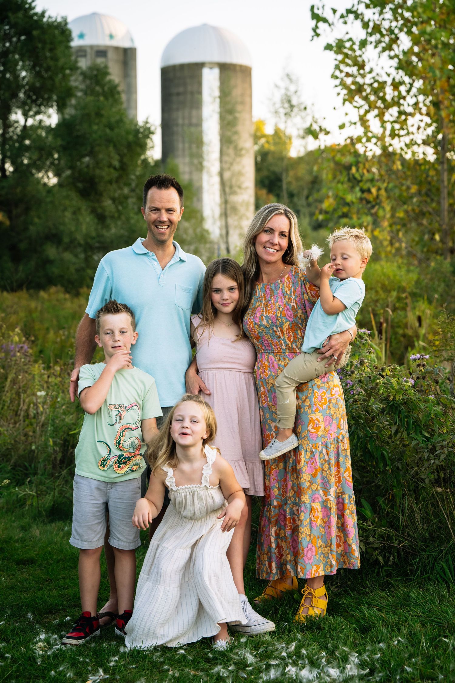 Family portrait session in a natural outdoor setting with wildflowers and greenery at sunset.