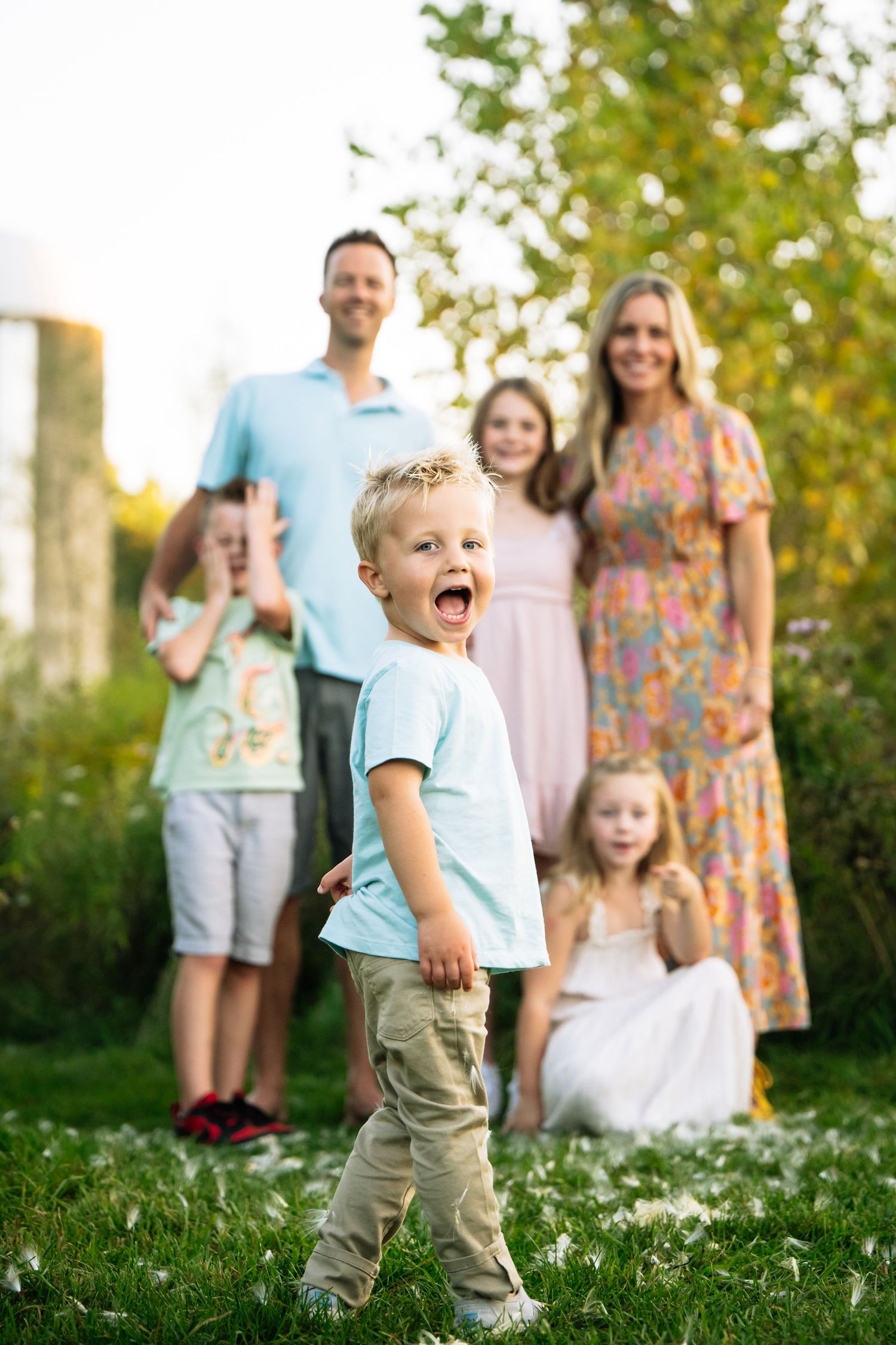 A group of people stands together in a grassy field on a sunny summer day.