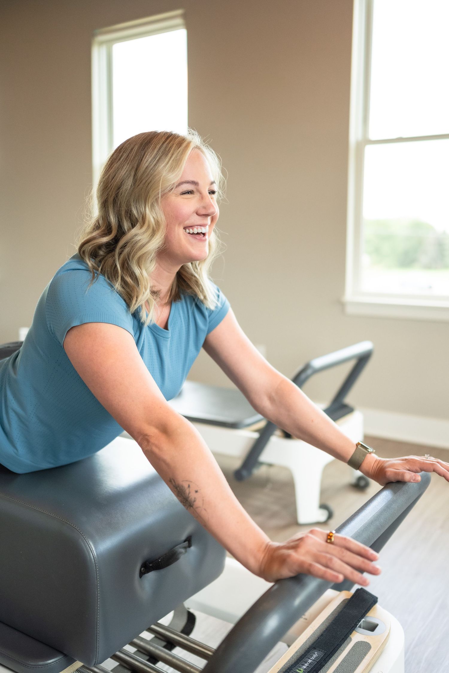 A person smiles while using a chiropractic adjustment table in a bright medical office setting.