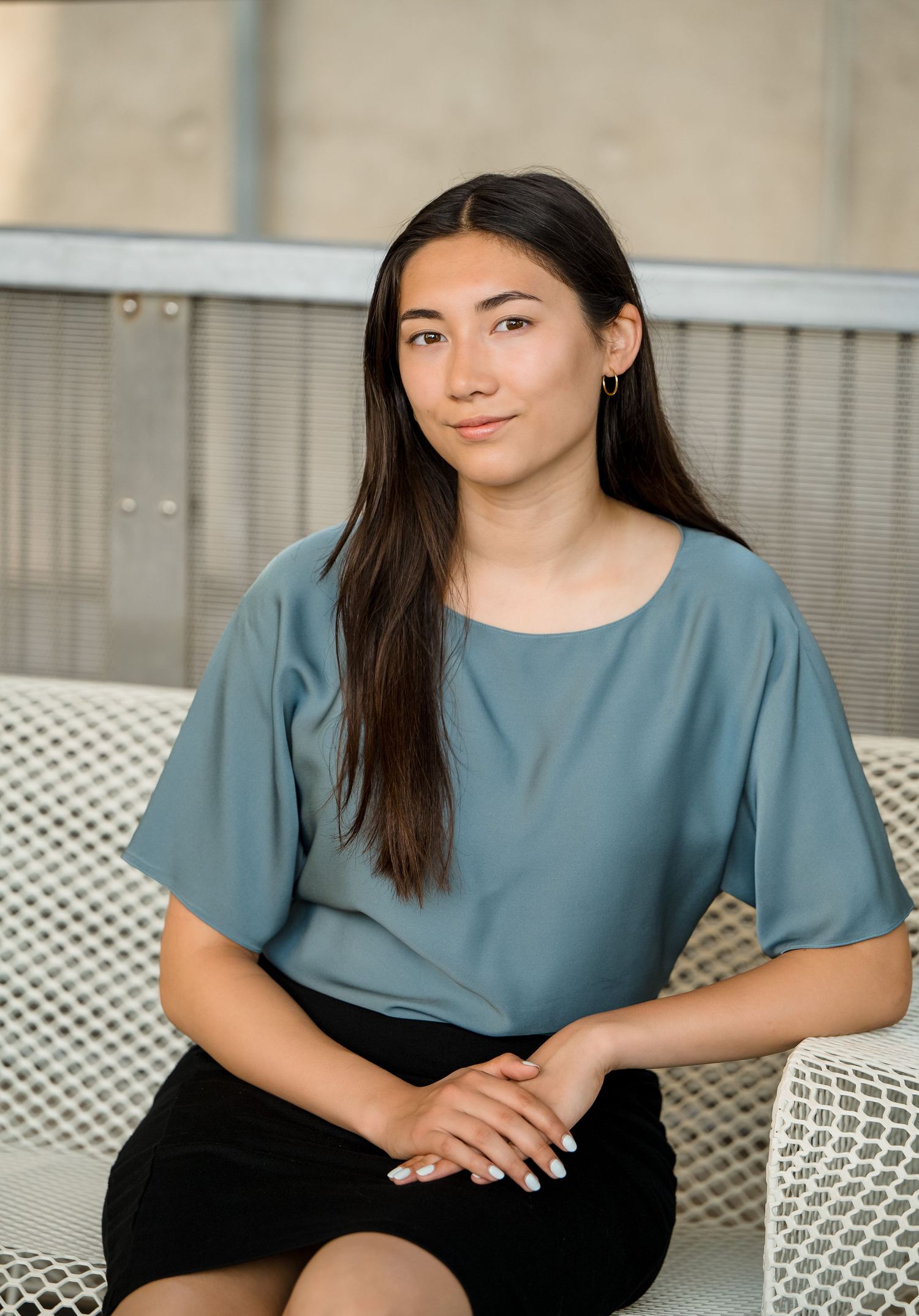 A person in a teal top and black pants sits casually on white outdoor furniture in a series of poses.