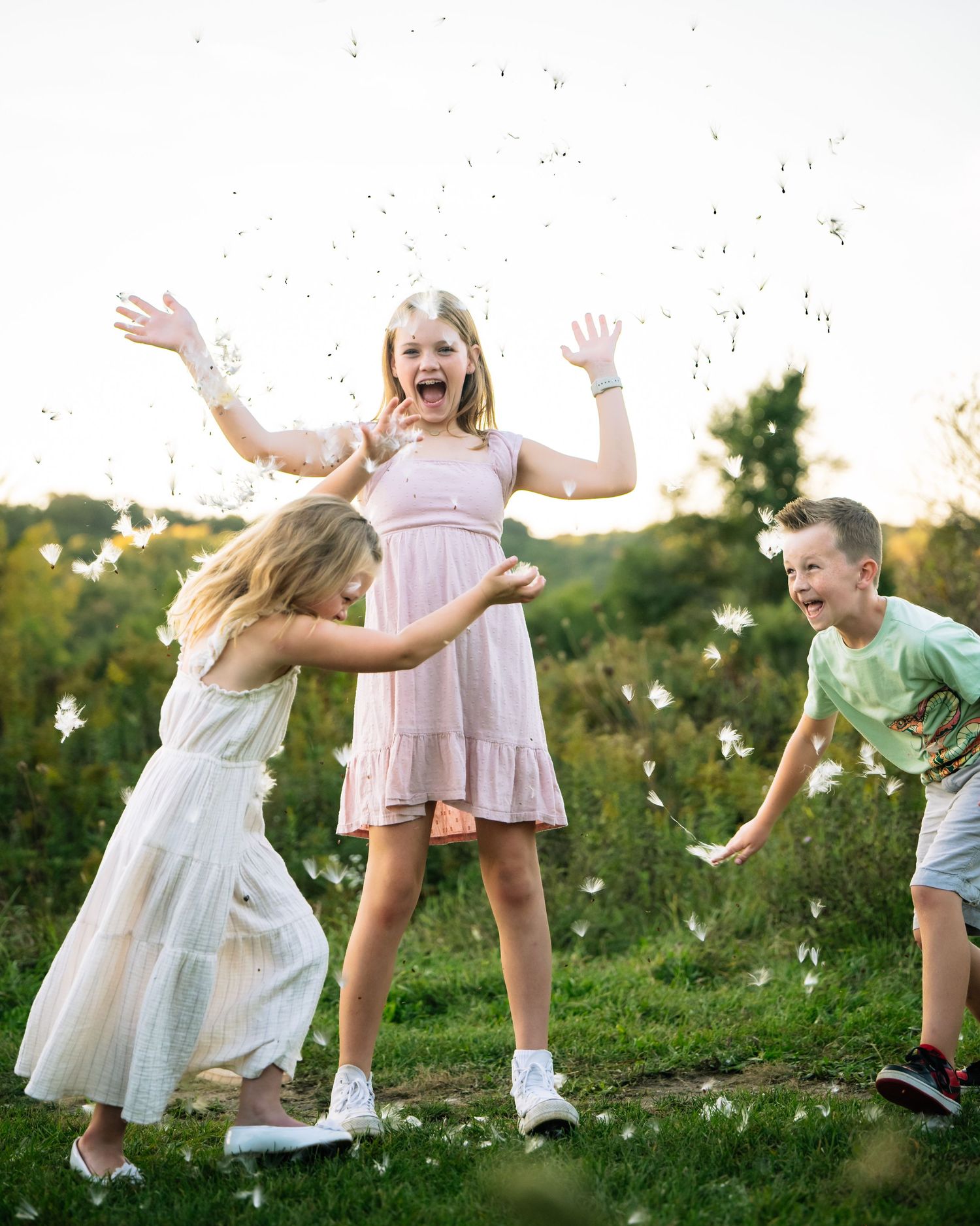 Children playing and jumping joyfully together in a grassy meadow during golden hour.