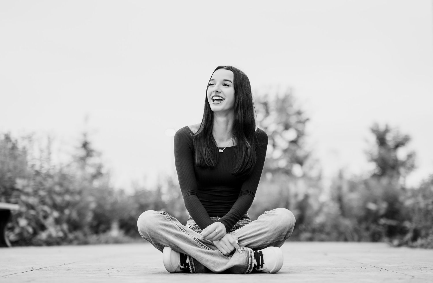 A black and white photo sequence shows a senior girl sitting cross-legged outdoors while laughing and enjoying a moment.