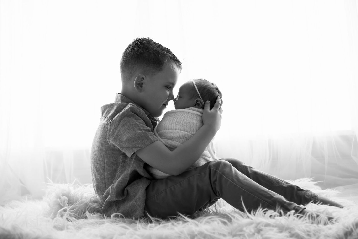 black and white image baby sleeping with brother holding her