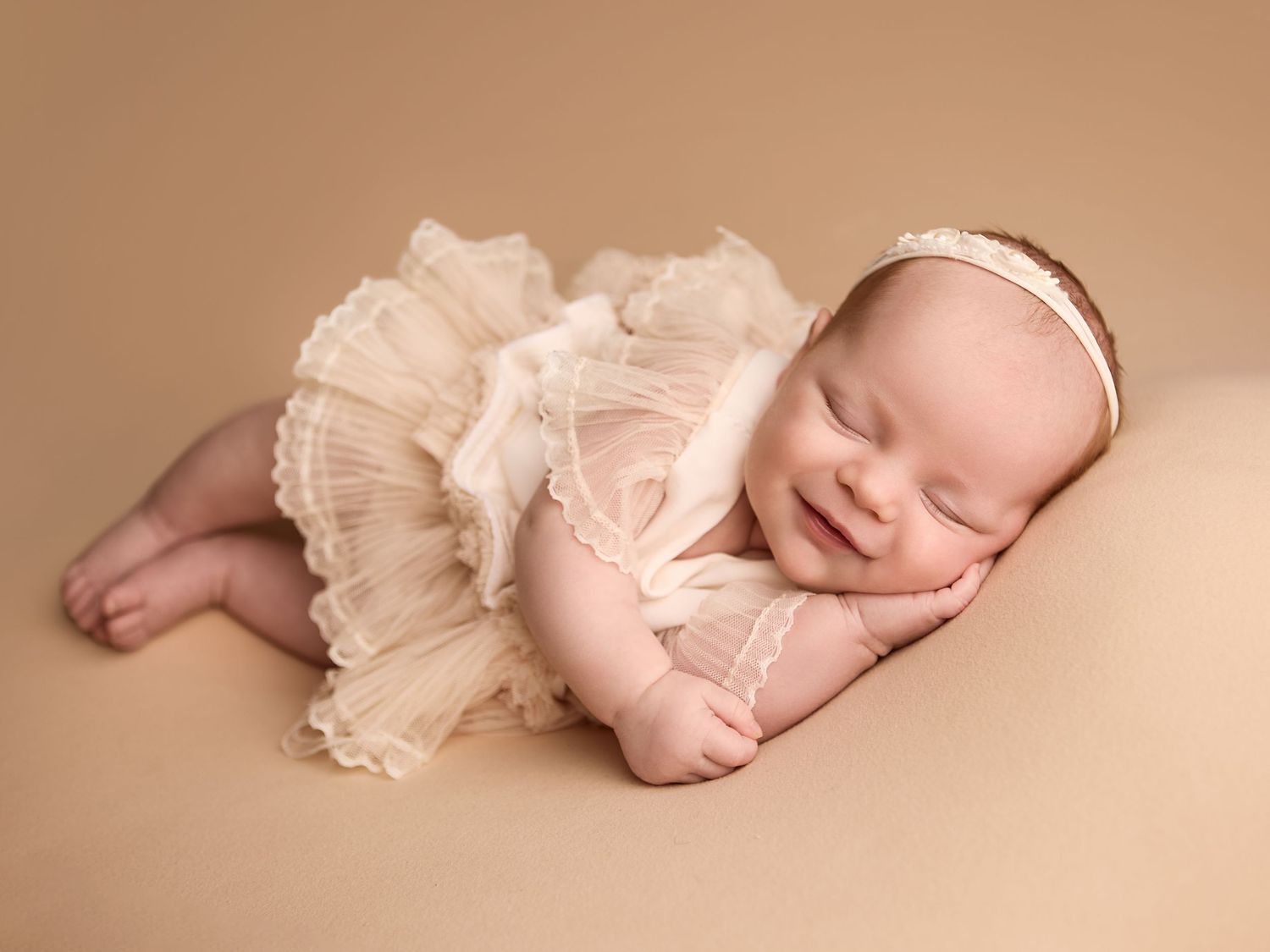 Newborn baby photography of a sleeping baby in a soft cream textured wrap