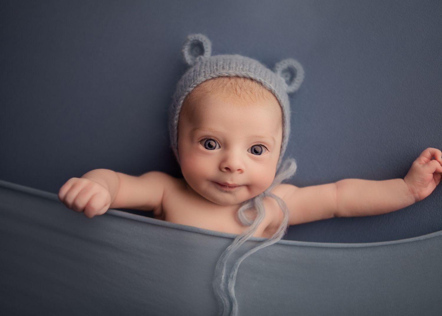 Newborn baby sleeping wrapped in a blue blanket during a newborn photography session