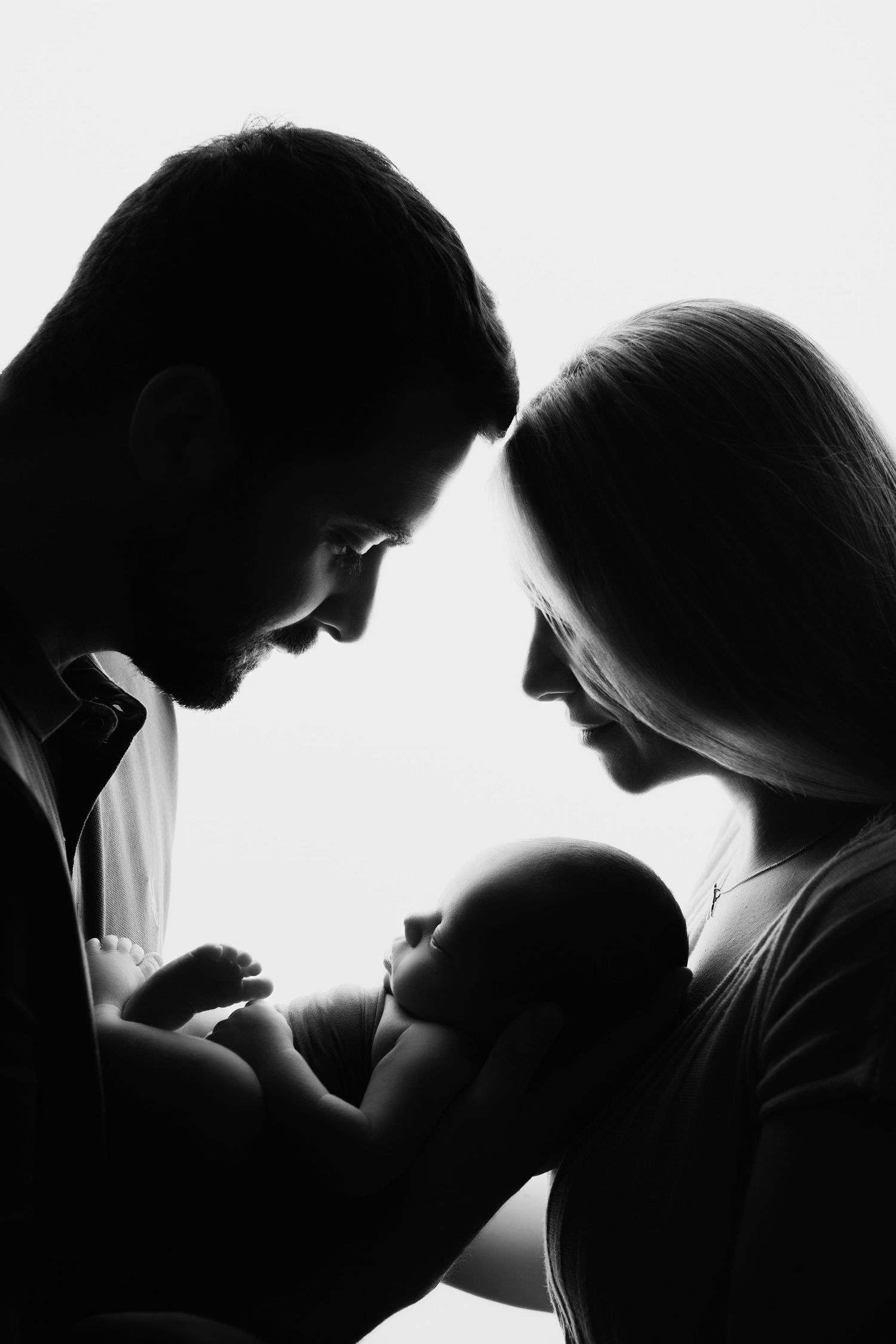 Newborn baby being held by mother and father during a natural newborn photography session in black and white