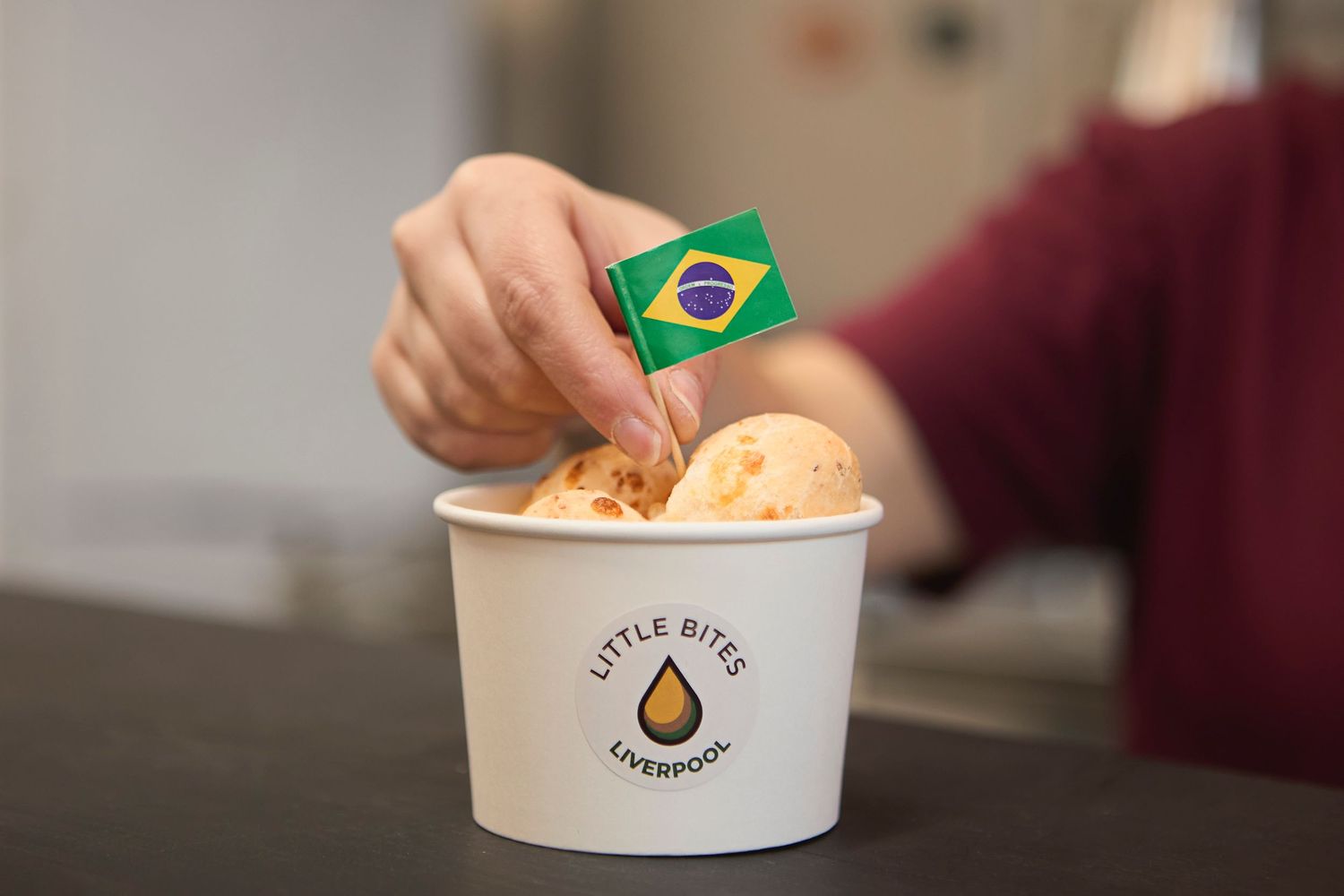 Commercial product photograph of a branded cup held by hand against a dark background