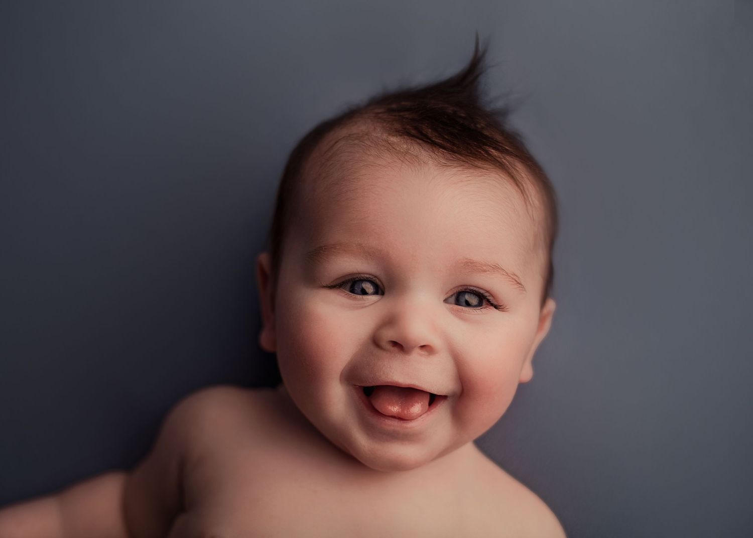 Newborn baby sleeping wrapped on a blue blanket during a newborn photography session