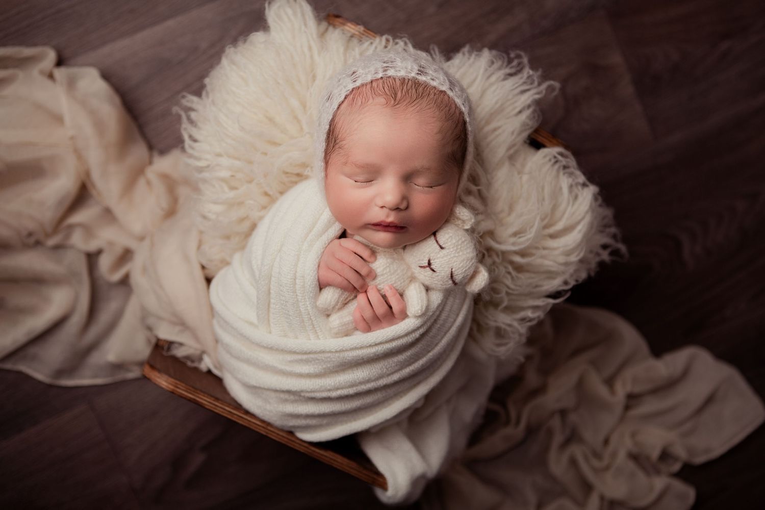 Newborn baby sleeping wrapped in a neutral blanket during a newborn photography session